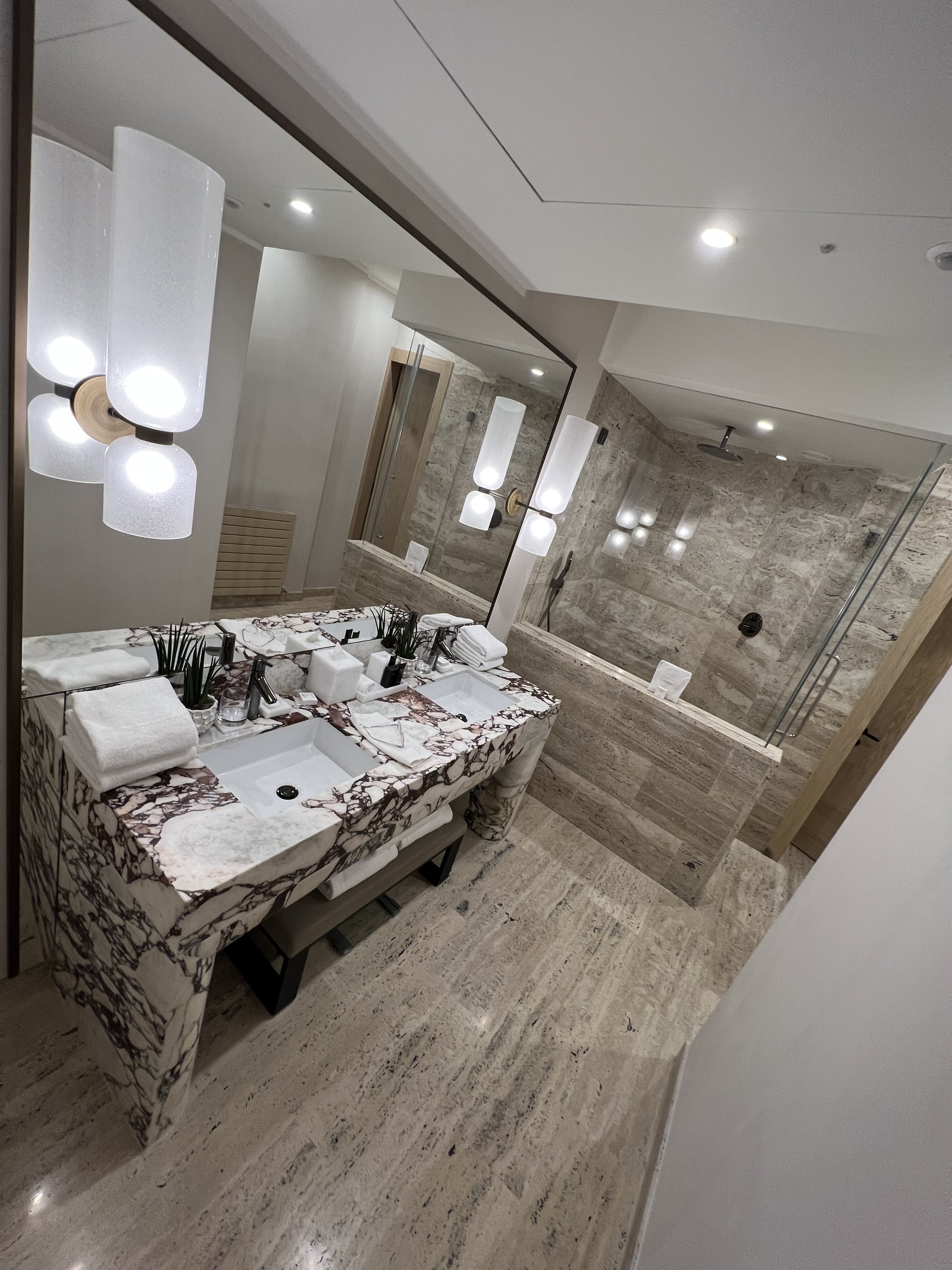 A walk-in shower with travertine walls and a rain head
