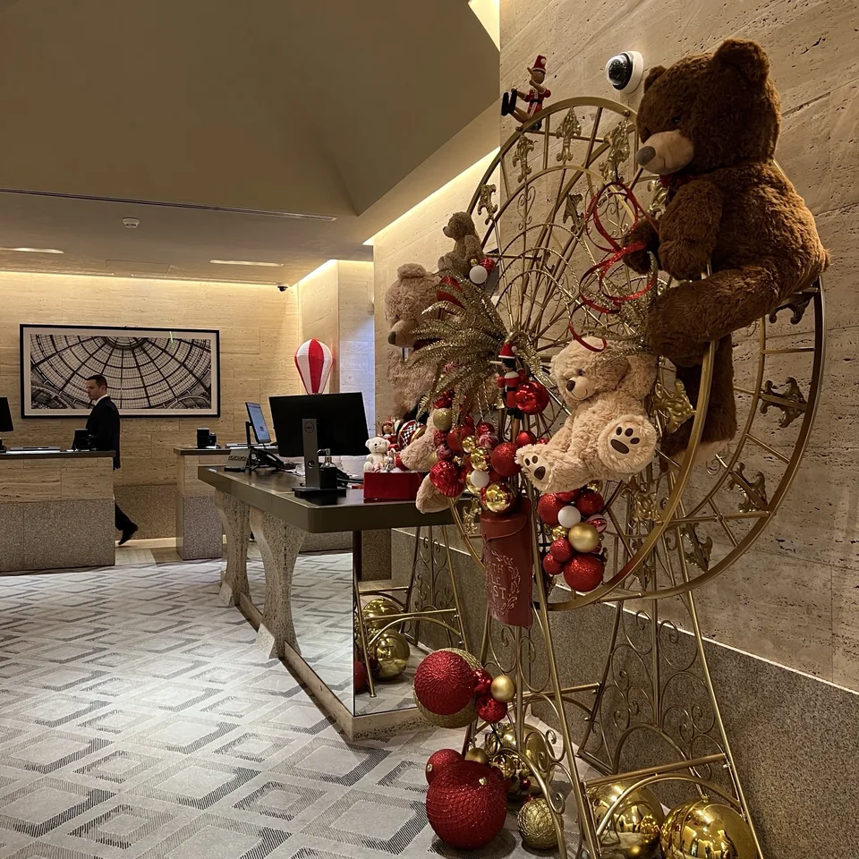 A gold Ferris wheel of teddy bears and red and gold baubles beside the reception desk in the lobby