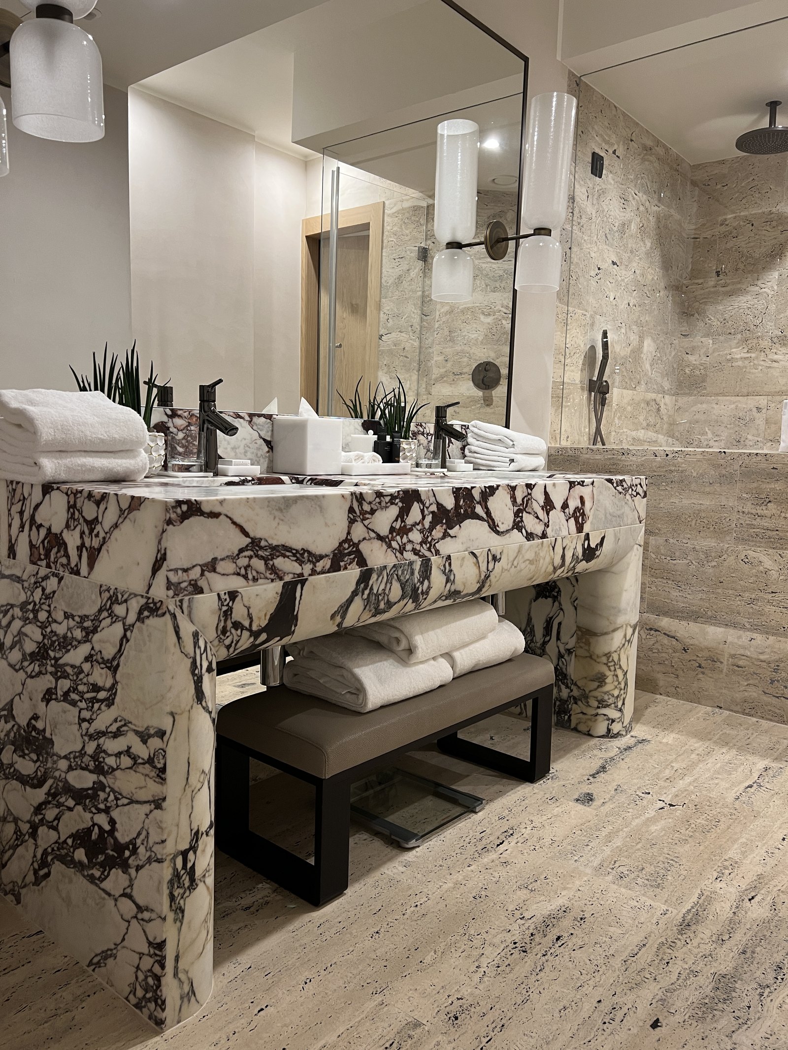 A marble vanity with towels folded beneath it and two wall lamps above