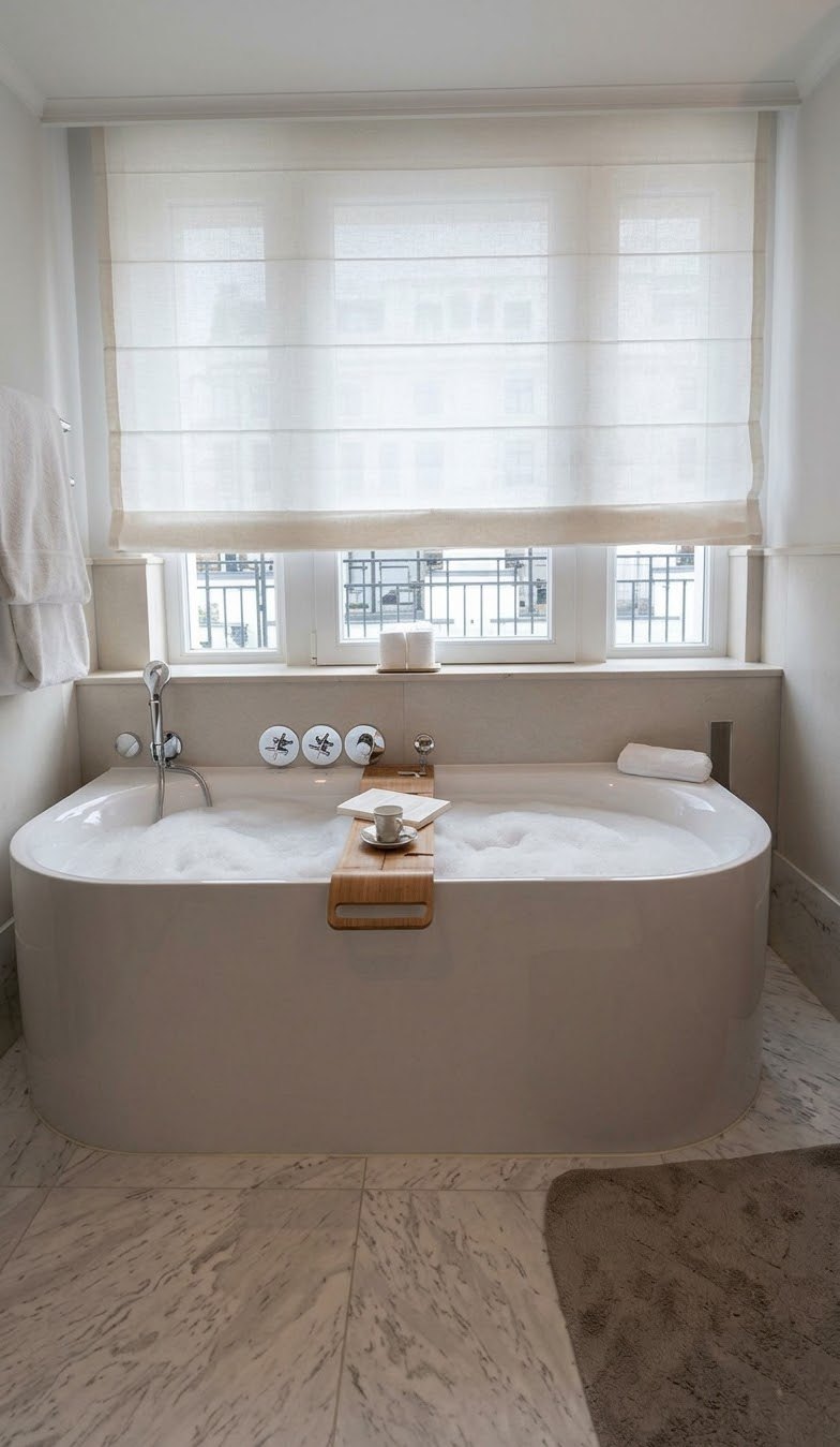 A freestanding bath under a shuttered window, a tray across it and a robe hanging beside