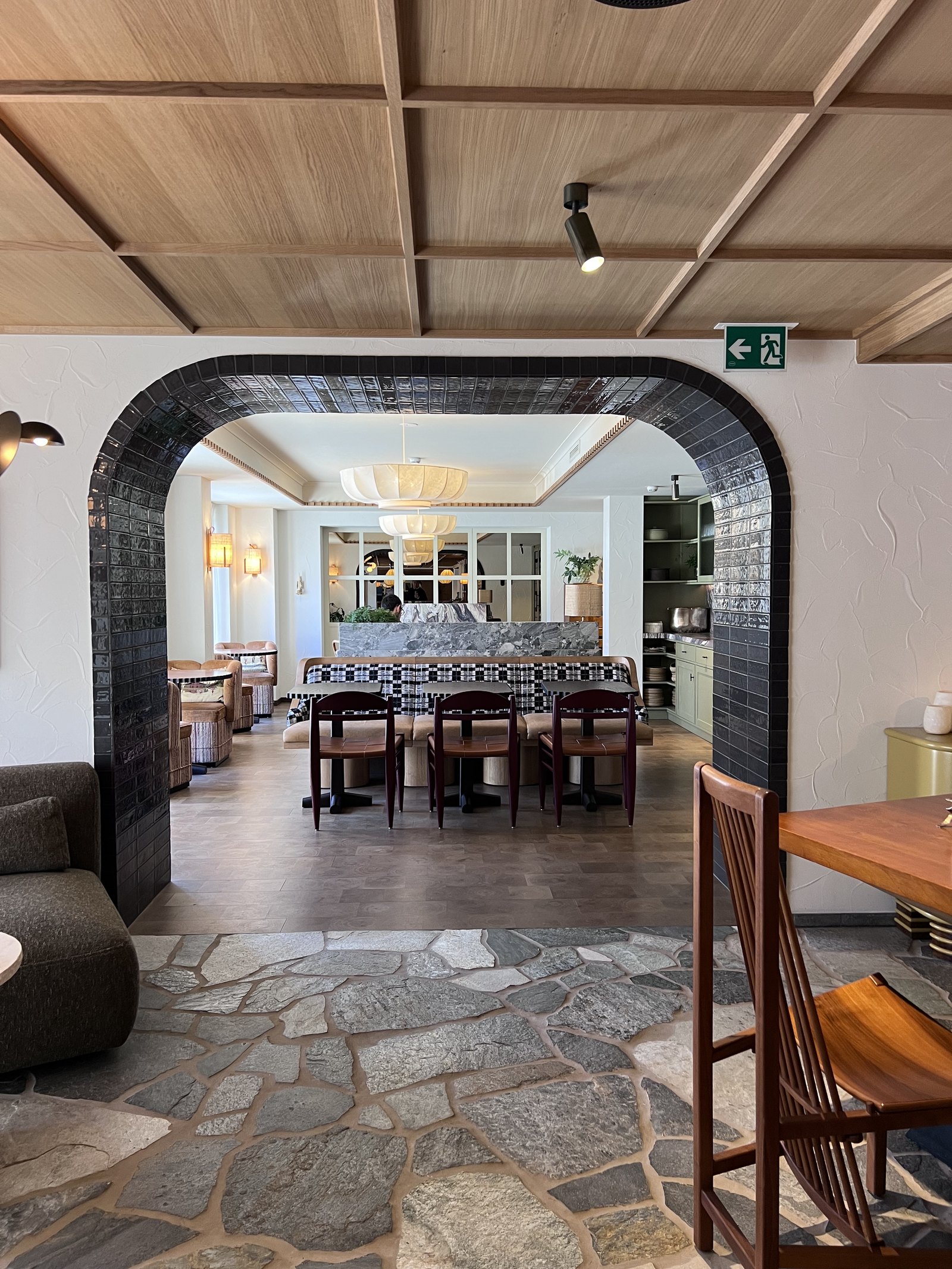 A stone flagged hall at The Brecon with a dark tiled arch opening onto the long dining table beyond
