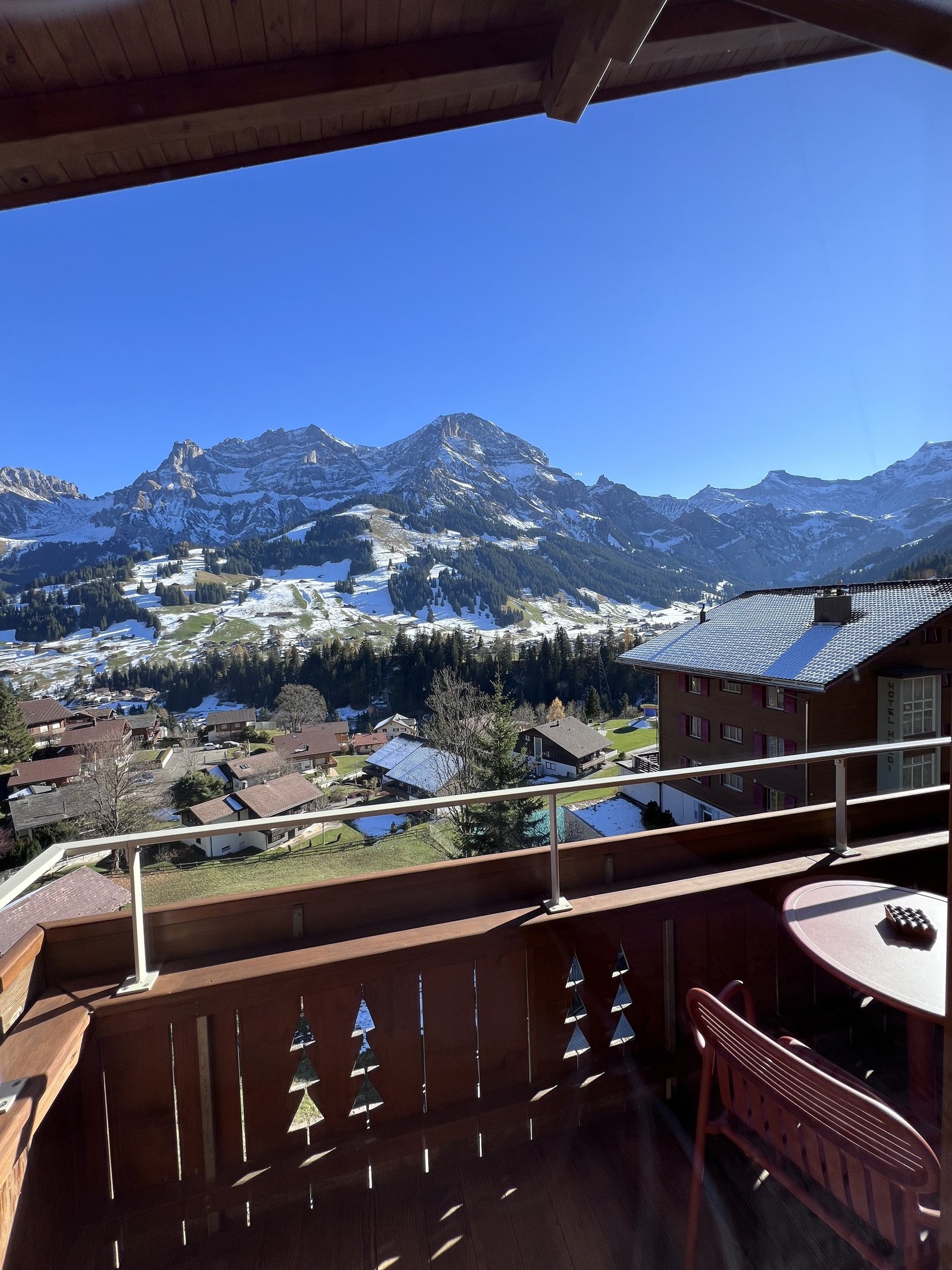 The view from the balcony at The Brecon over the village roofs to the snow on the peaks, with the carved timber balustrade in front