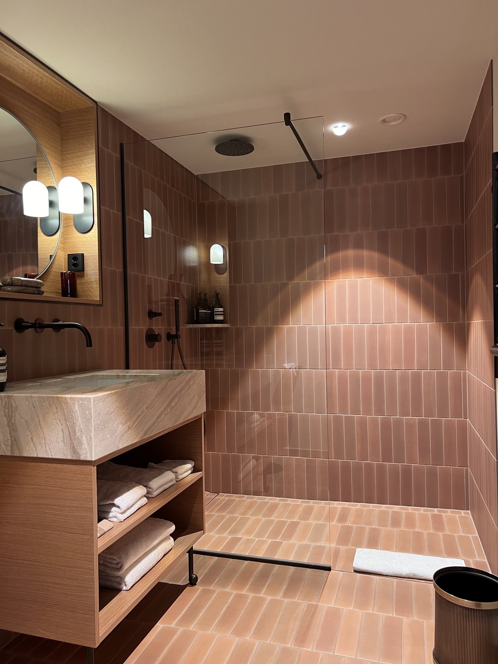 A bathroom at The Brecon with terracotta tiling, a stone basin on a timber vanity and a walk-in shower