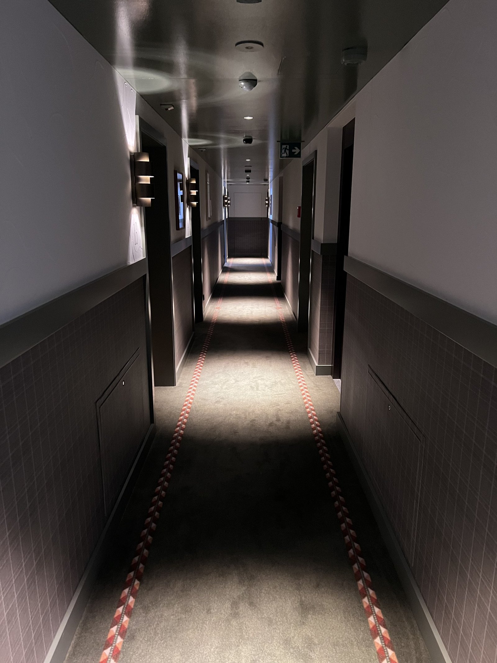 A dark timber corridor at The Brecon lit low along the floor with a red striped runner