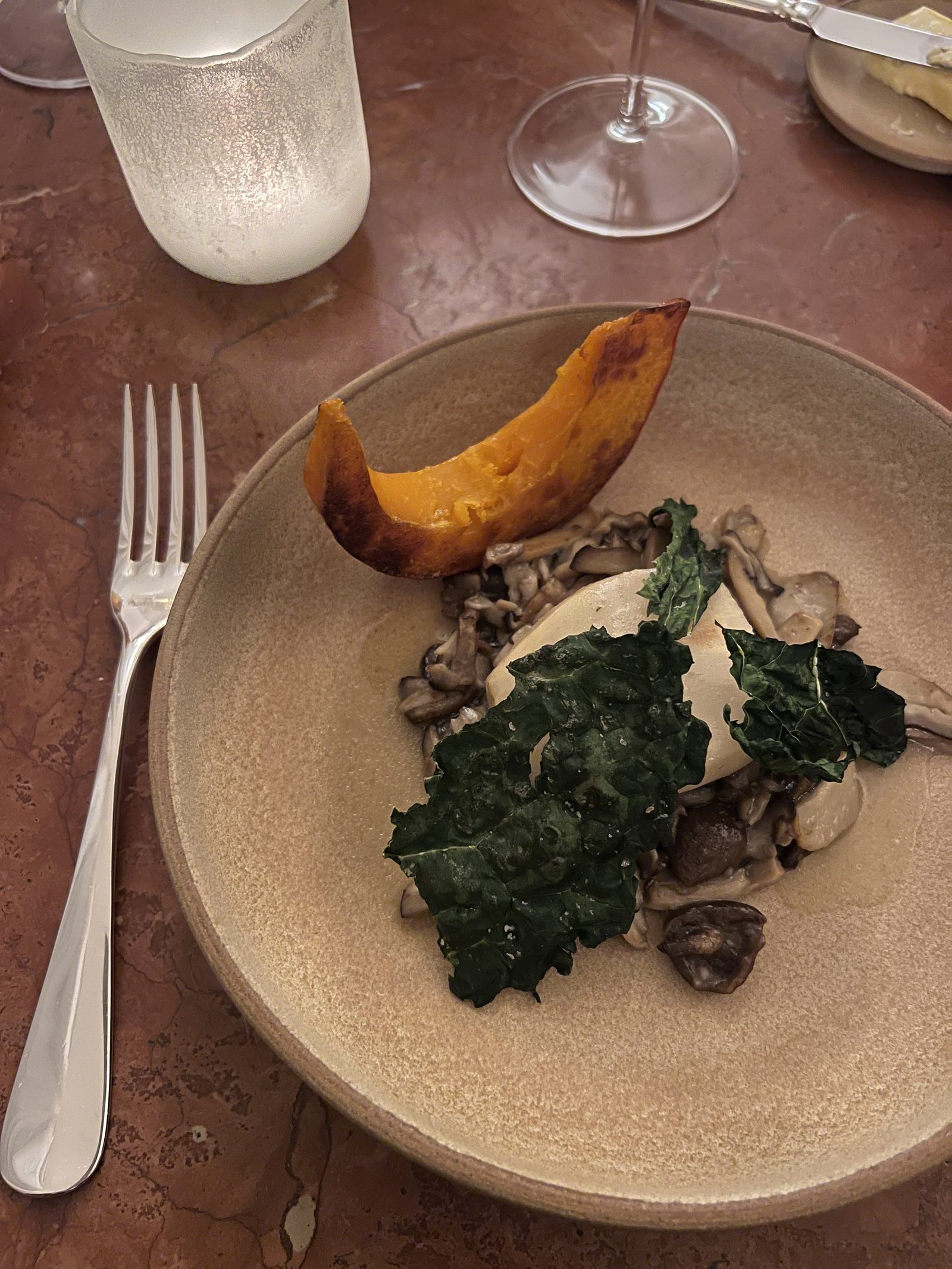 A plate of braised greens and meat on a ceramic dish with a fork