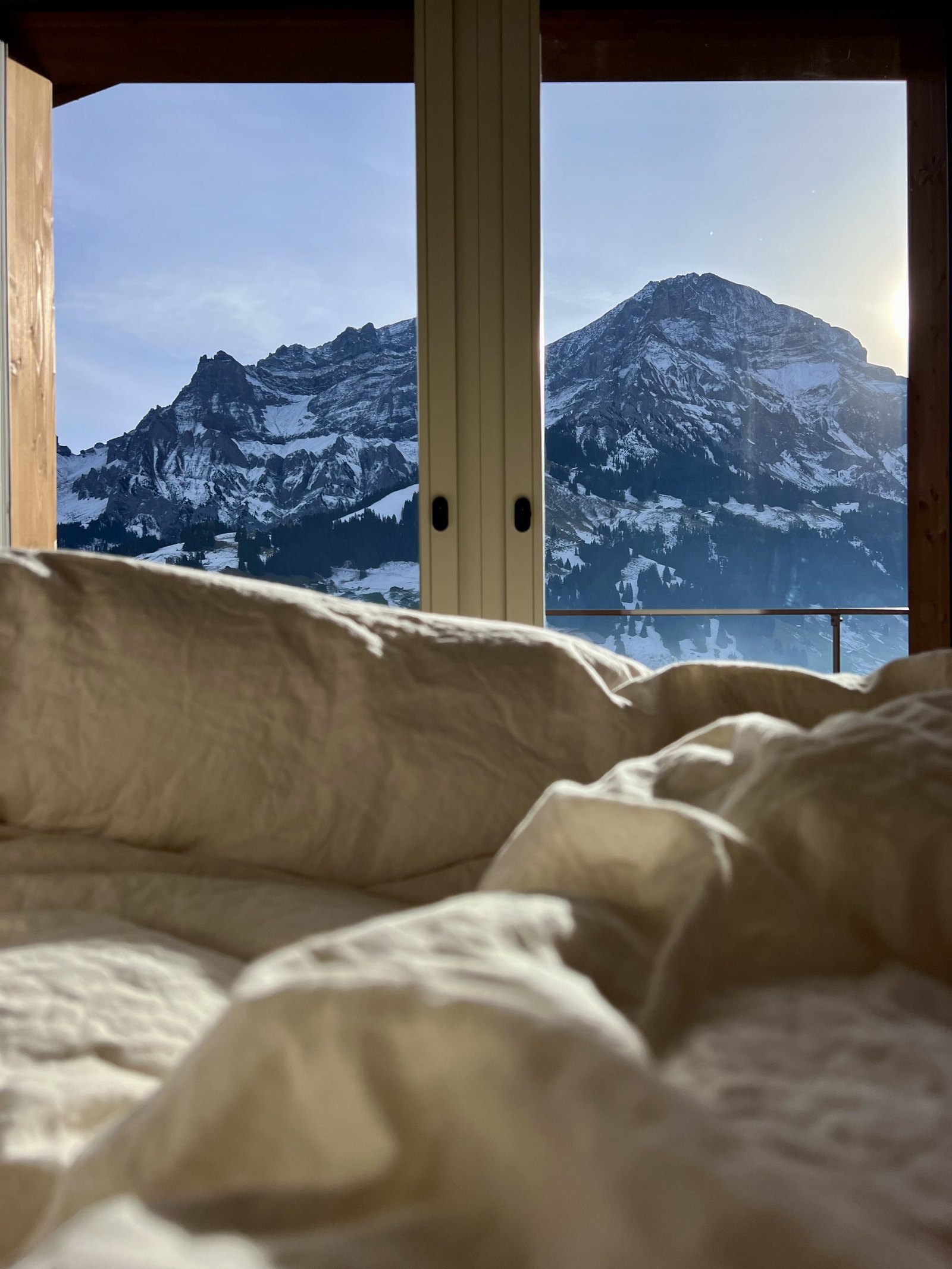 The mountain framed in the bedroom window seen from the bed past the duvet