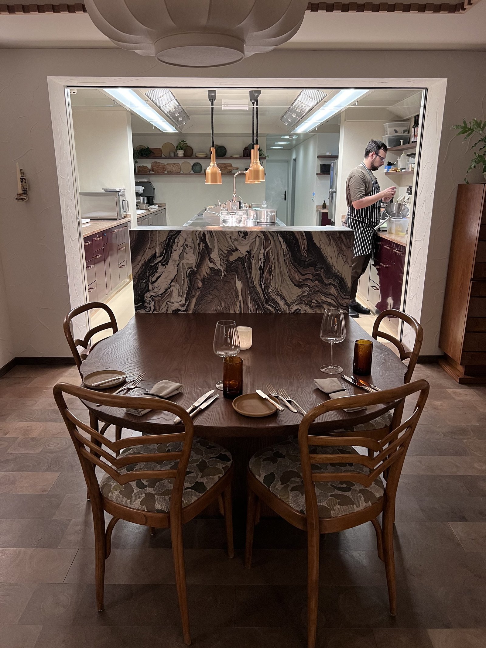 The open kitchen at The Brecon with a marble counter, pendant lights and a round table with bentwood chairs