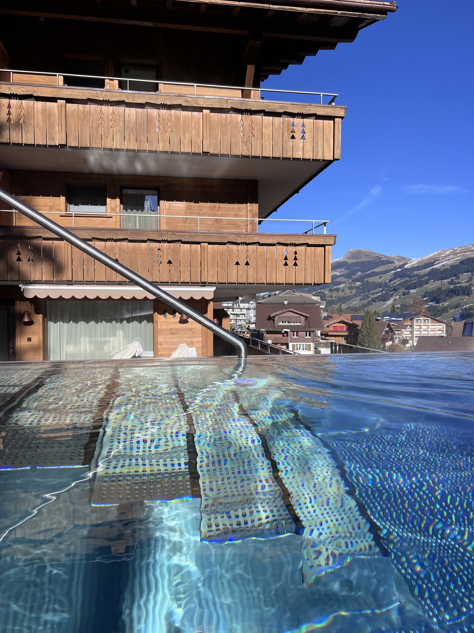 The heated outdoor pool steaming beneath the timber facade of the hotel