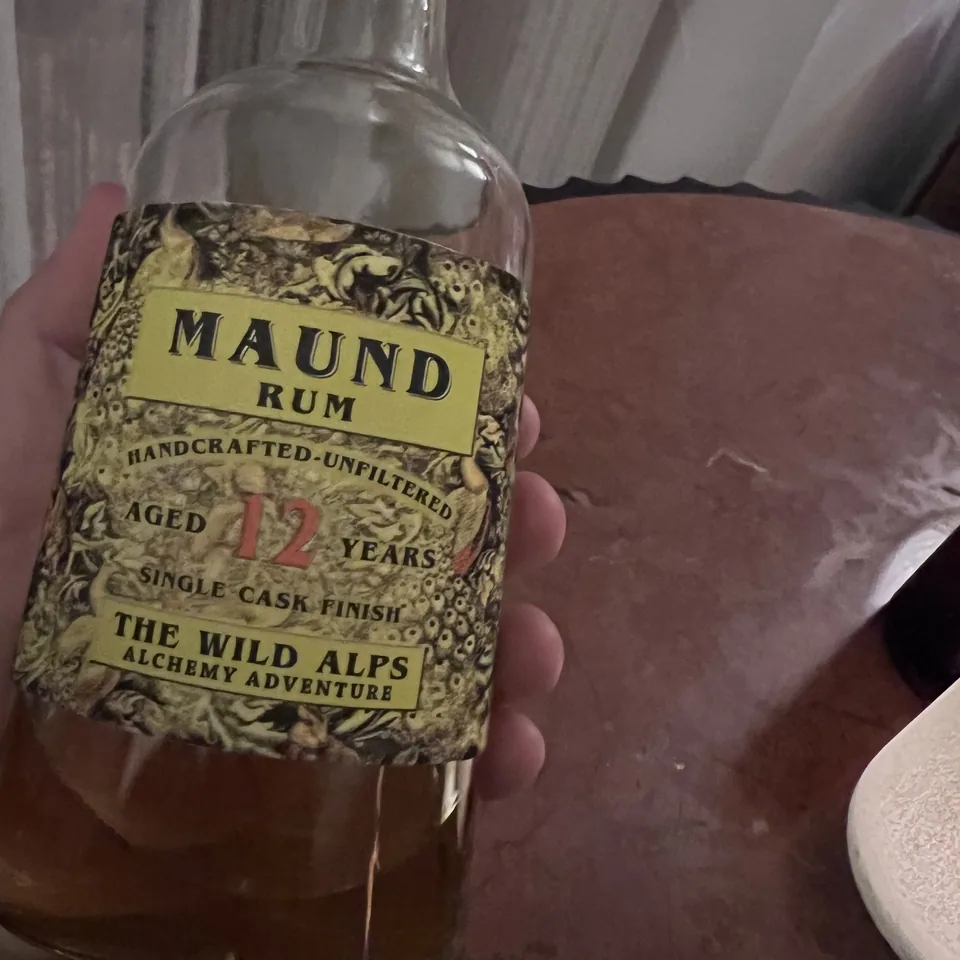 A bottle of Maund rum, distilled in the Alps, held up in one hand