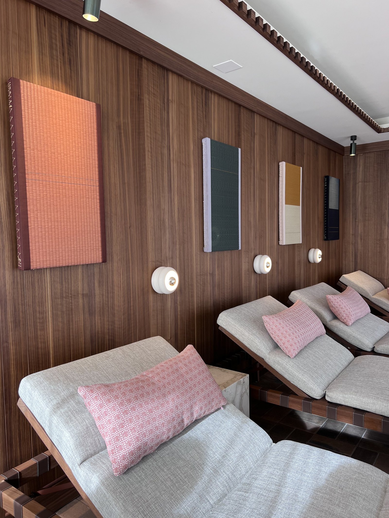 Loungers with pink cushions in a timber lined relaxation room with colour panels
