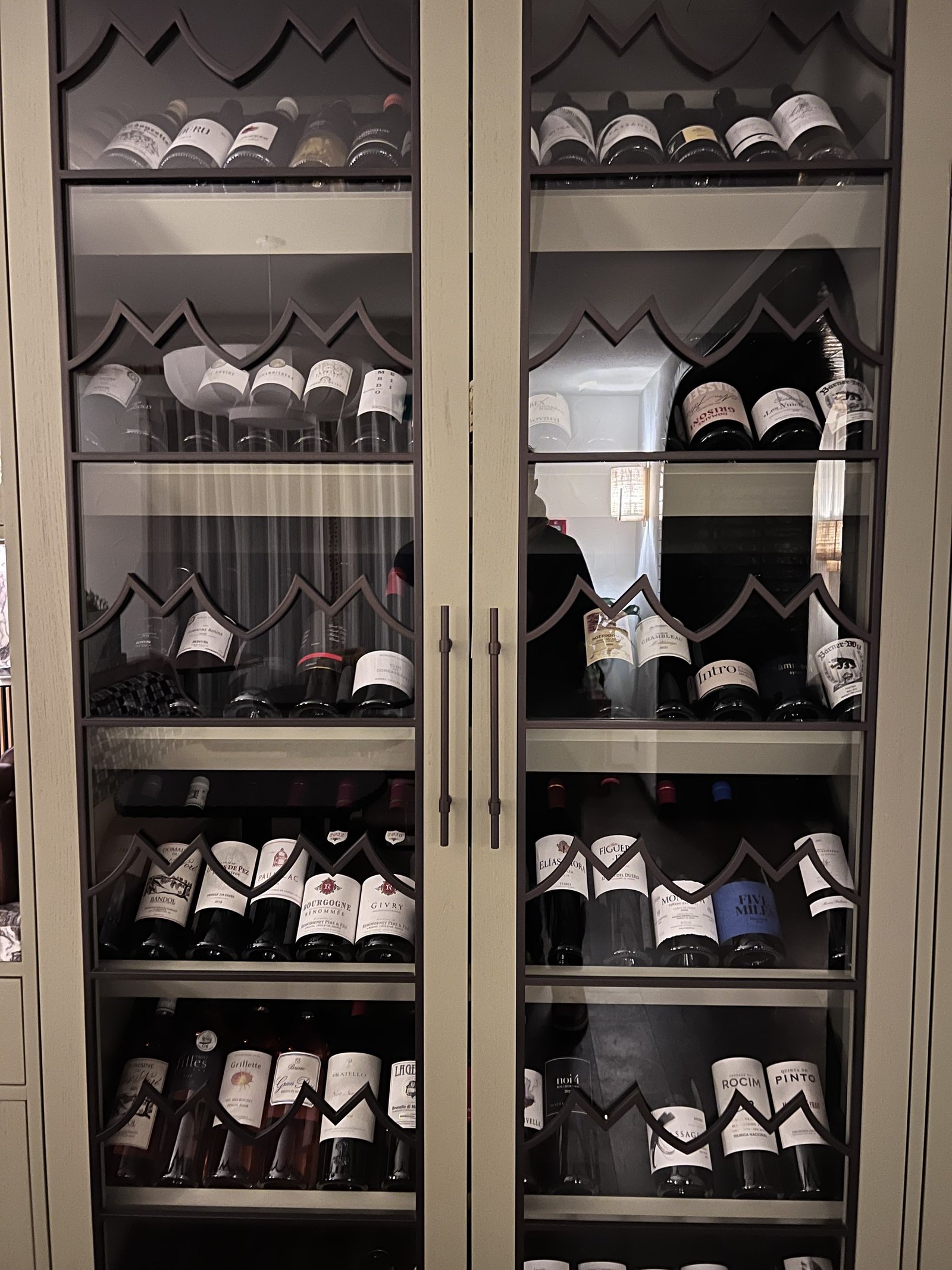 A tall glass fronted cabinet of wine bottles lit from within