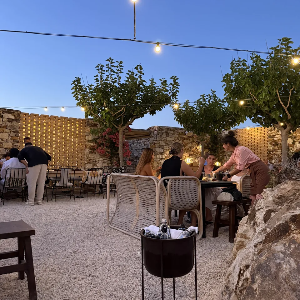 The restaurant courtyard at The Rooster after dark, with strings of lights overhead, guests at the tables and a wine cooler in the foreground