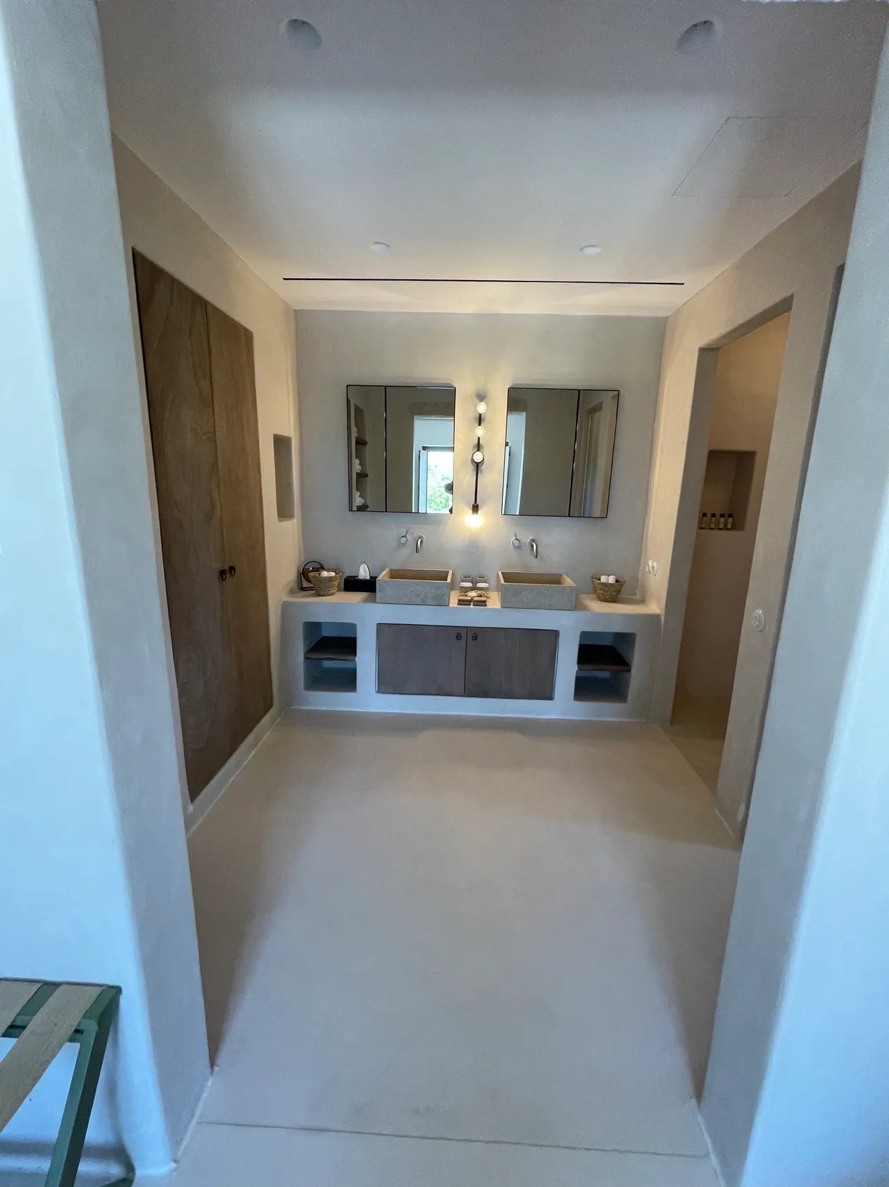 Two basins side by side under separate mirrors in an open-plan bathroom at The Rooster, with a timber door beyond