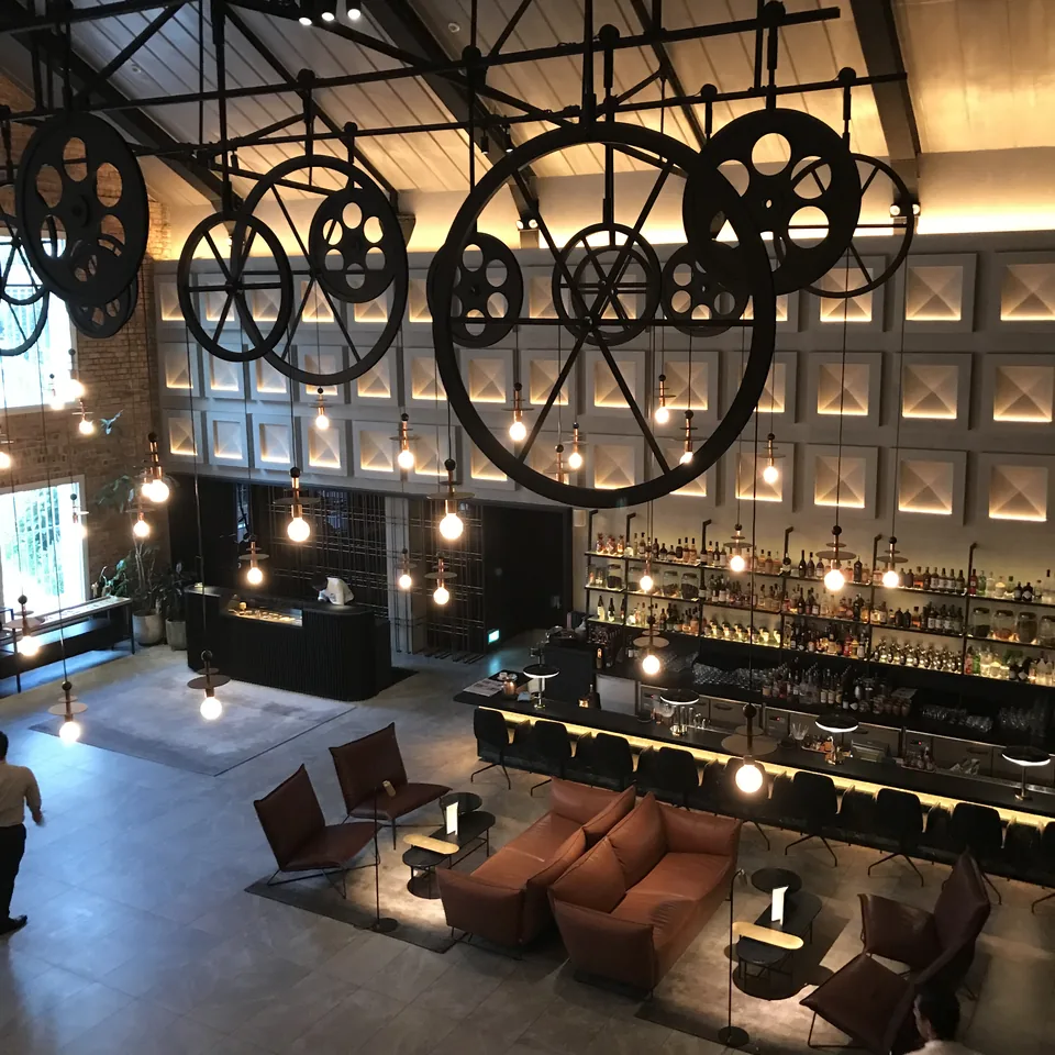The lobby bar seen towards the brick end wall, with tall shuttered windows and pendant bulbs