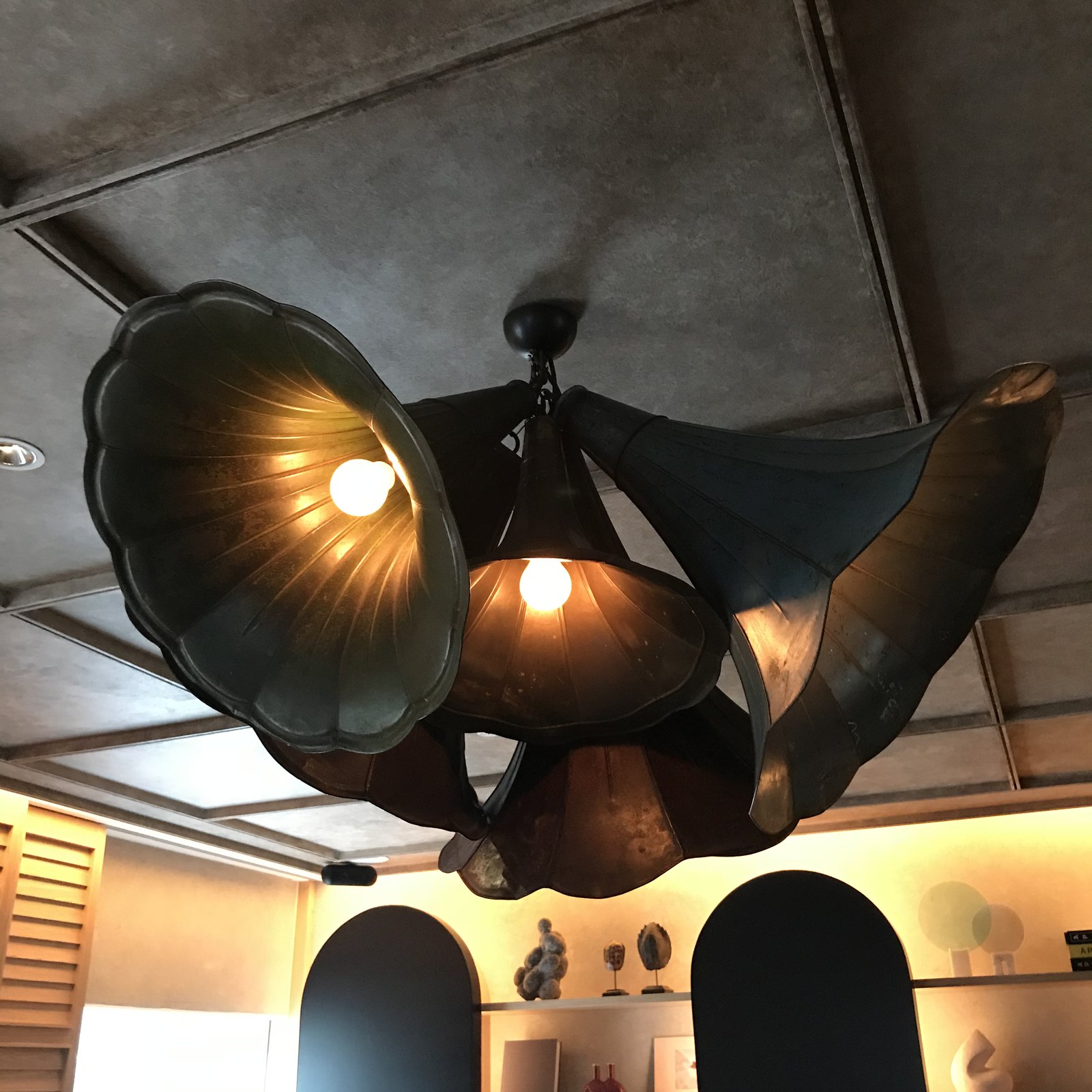A cluster of brass gramophone horns turned into a ceiling light, glowing from inside