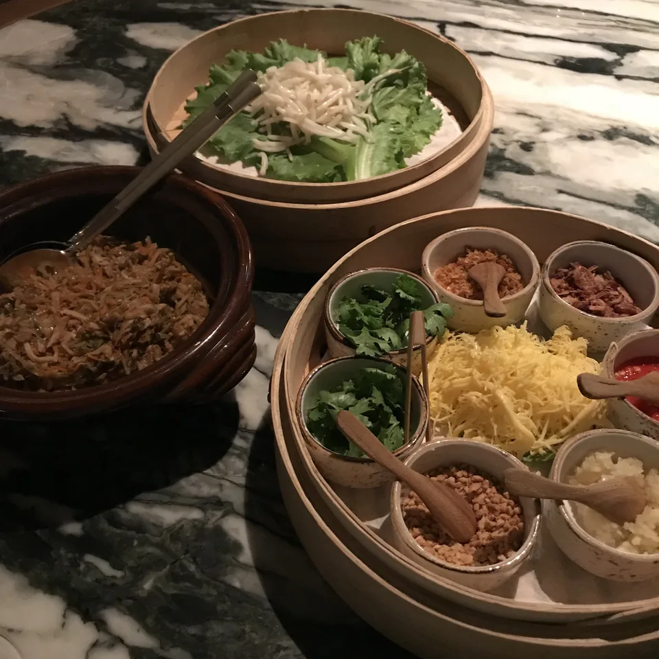 Steamer baskets and small bowls of popiah fillings on a marble table