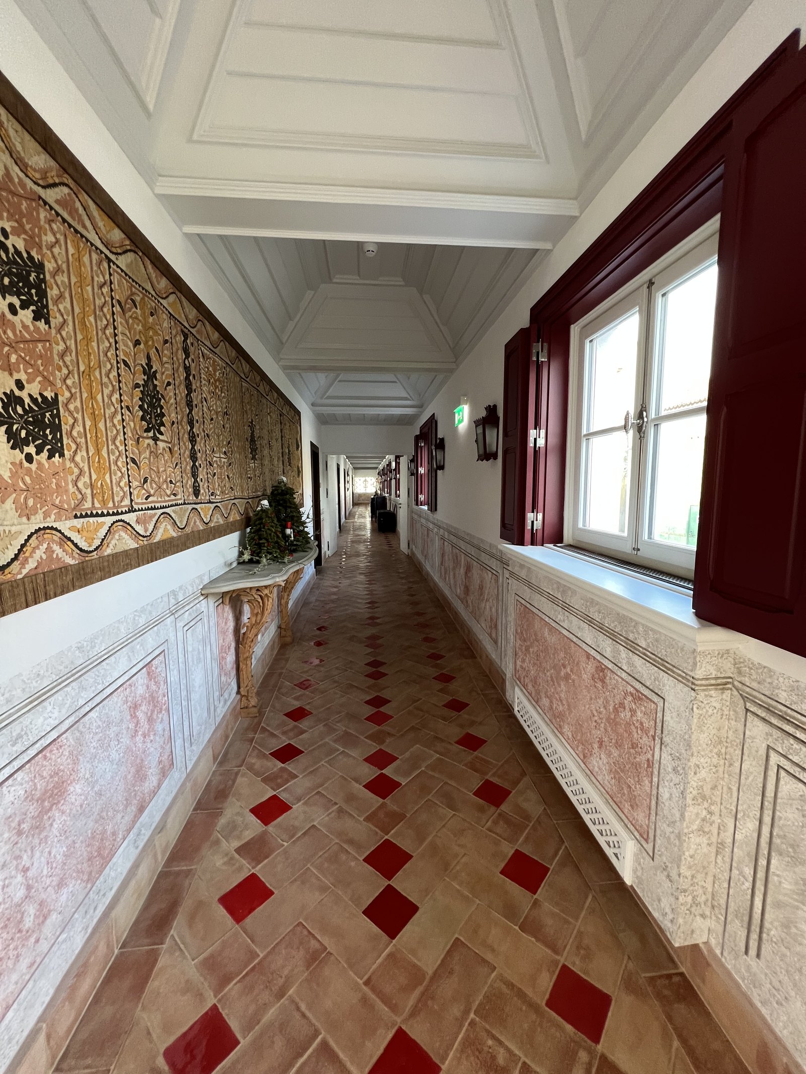 A long corridor at Vermelho with a red and white diamond tiled floor and frescoed walls