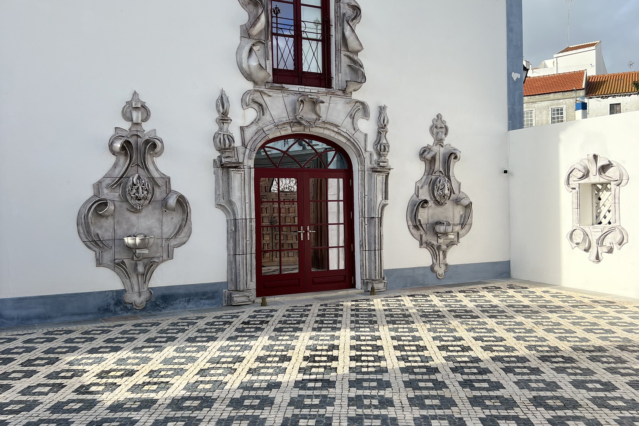 The carved stone door surround and wall panels at Vermelho above a courtyard paved in black and white tiles