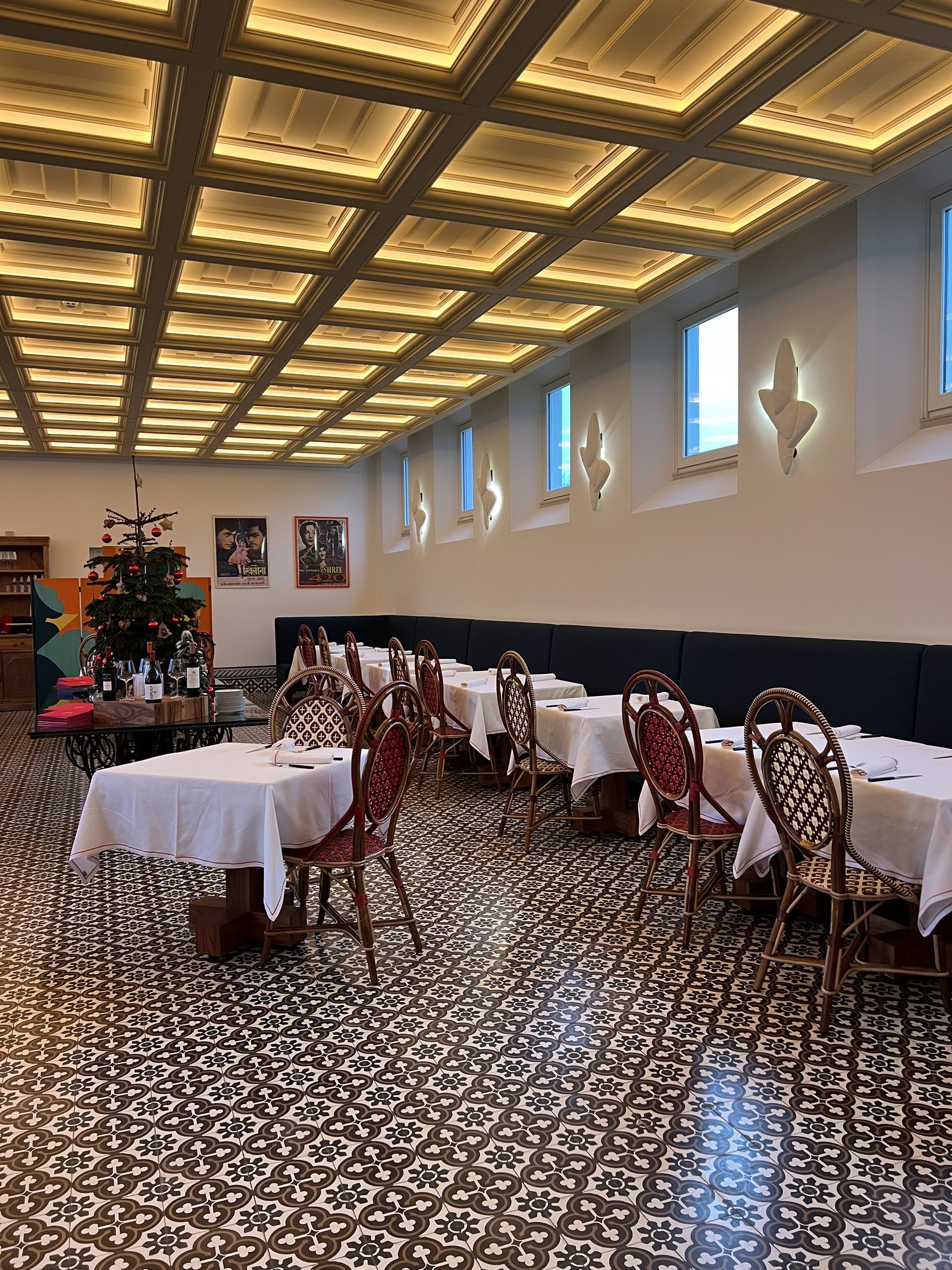 The dining room at Xtian with a coffered ceiling, patterned floor and tables laid in white