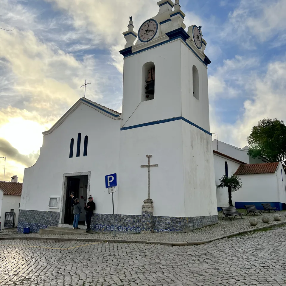 The whitewashed church of Melides with its blue trimmed bell tower above the cobbled square