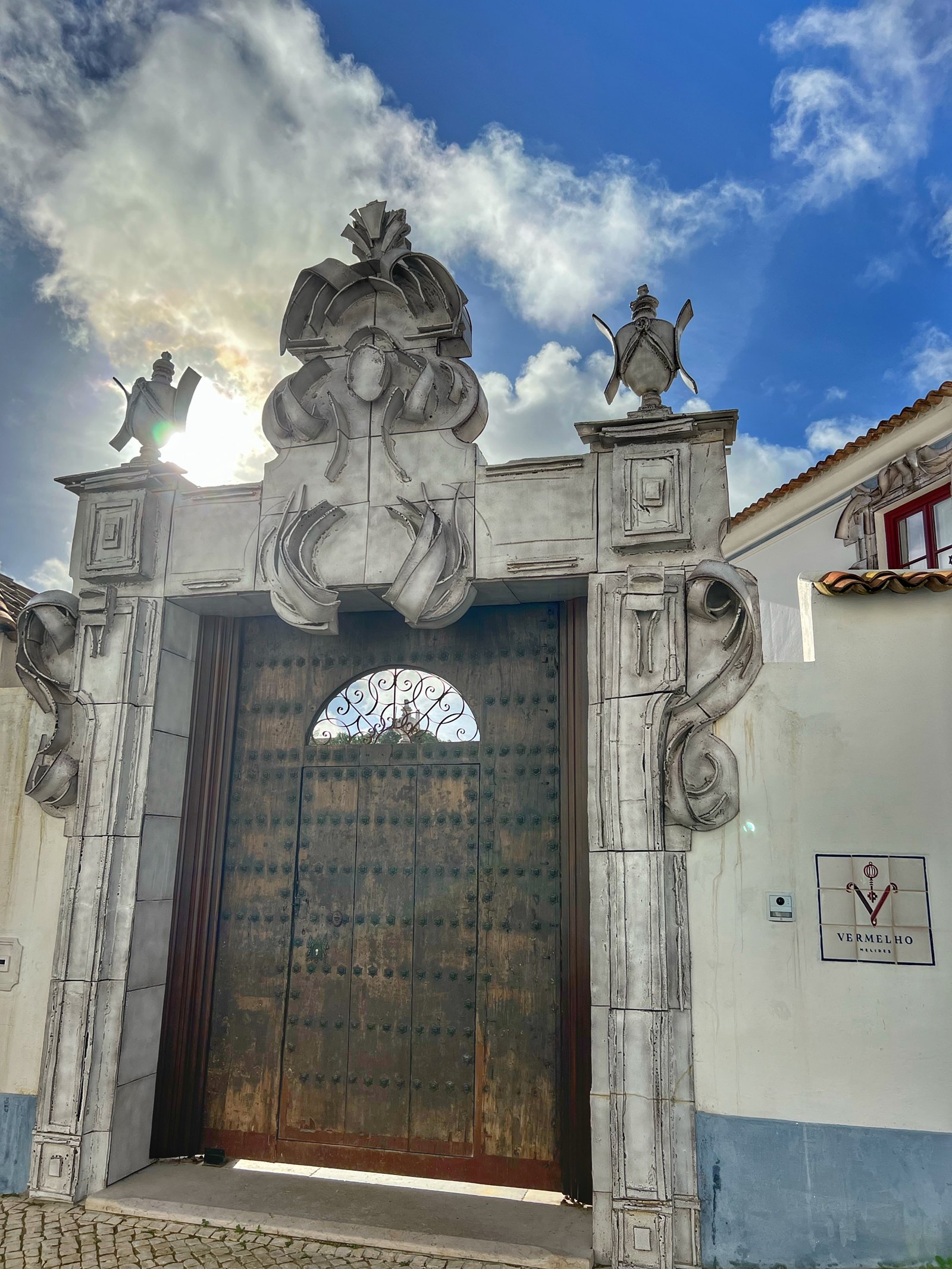 The carved stone gateway at Vermelho with its studded timber door and the Vermelho sign beside it