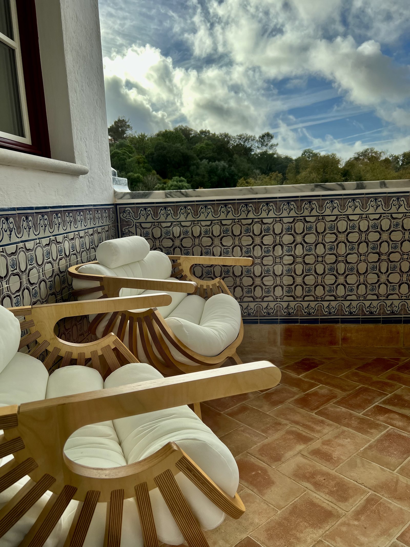 Two sunburst timber loungers with white cushions on a terracotta terrace against a wall of azulejos
