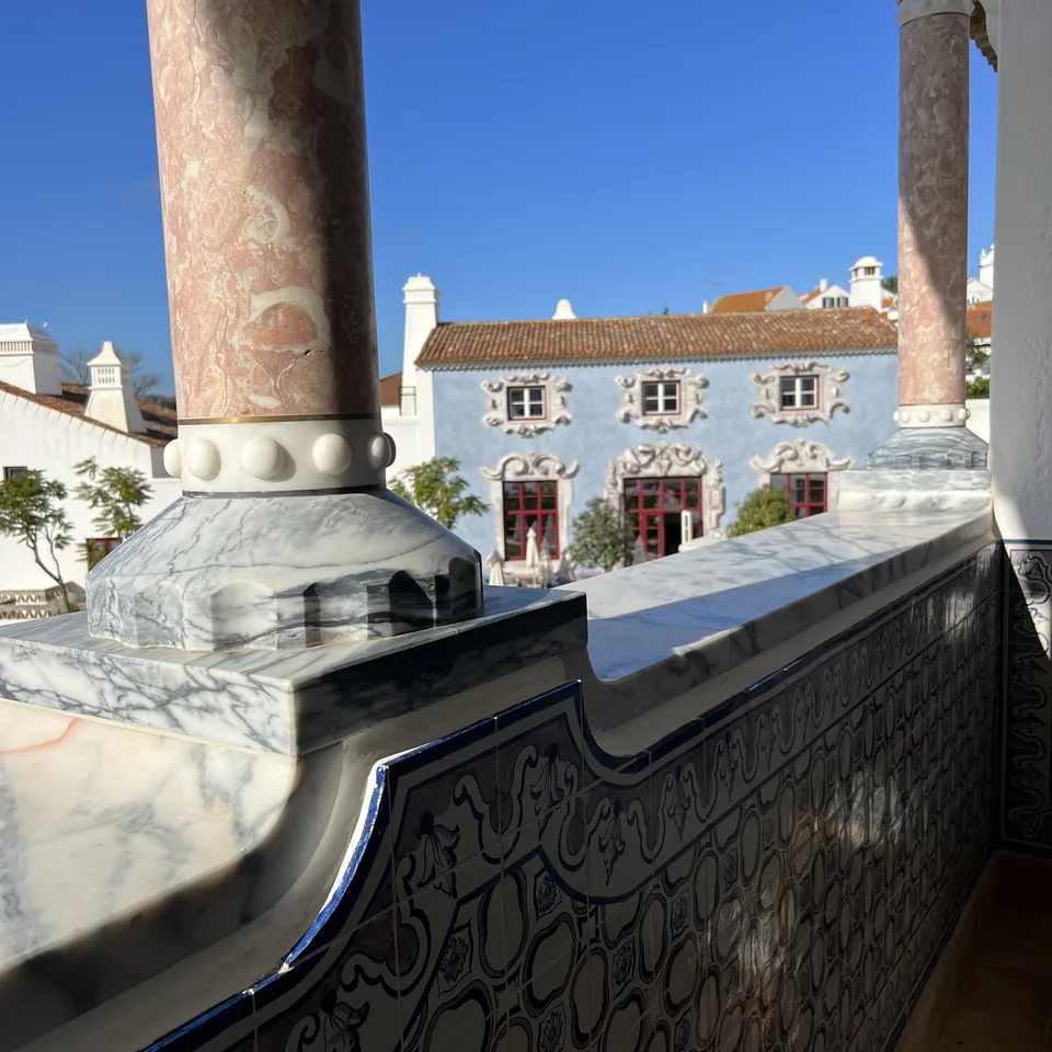 A marble balustrade and stone column on an upper terrace looking over the white rooftops