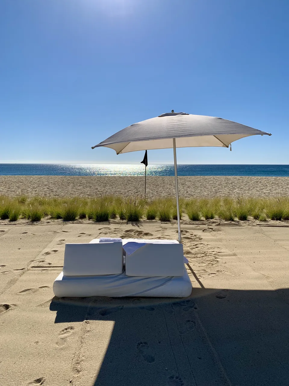 A double daybed under a parasol on empty sand at Viceroy Los Cabos