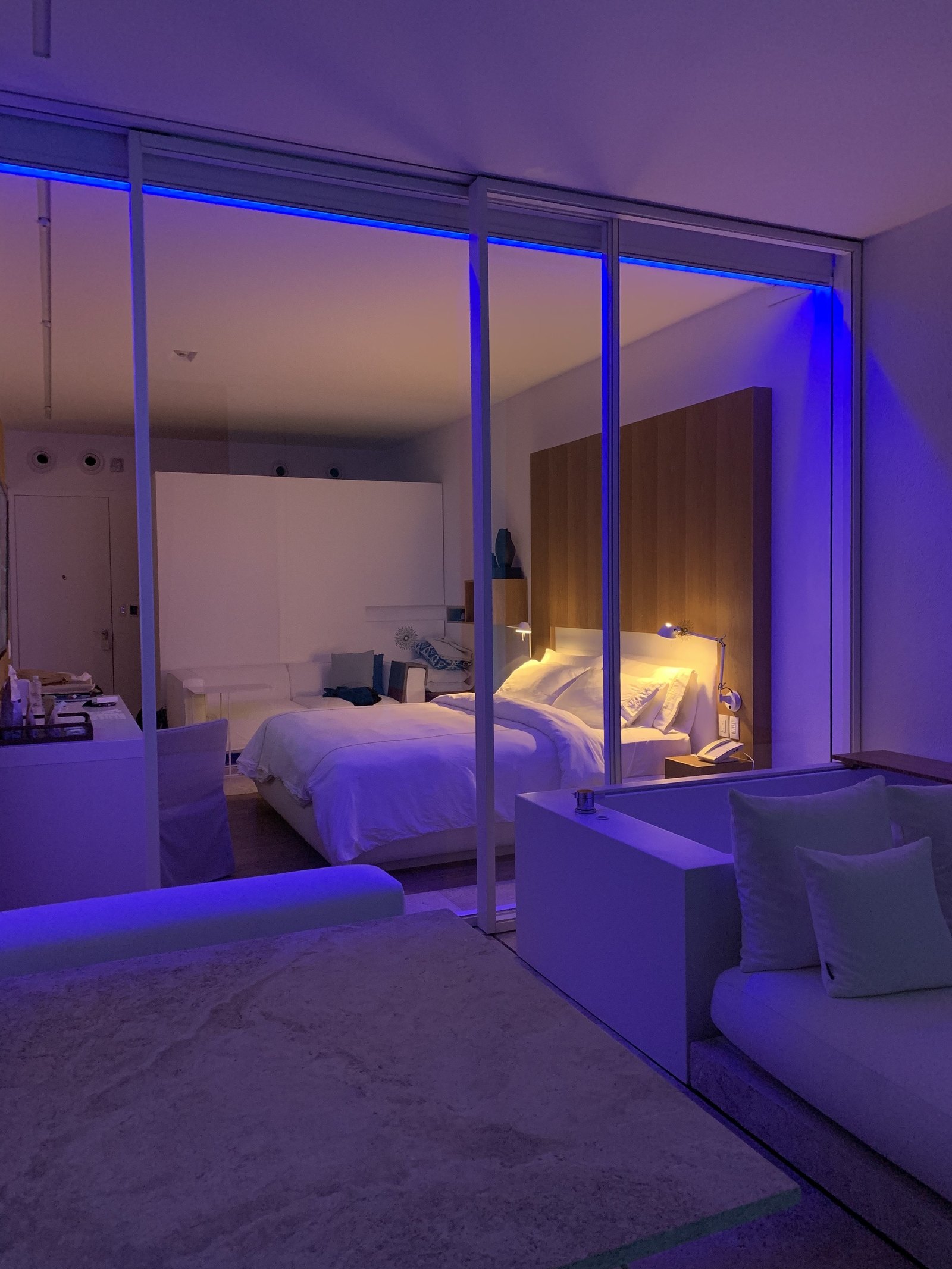 A room at Viceroy Los Cabos after dark, lit blue and violet along the walls and the ceiling, with the bed pale in the middle of it