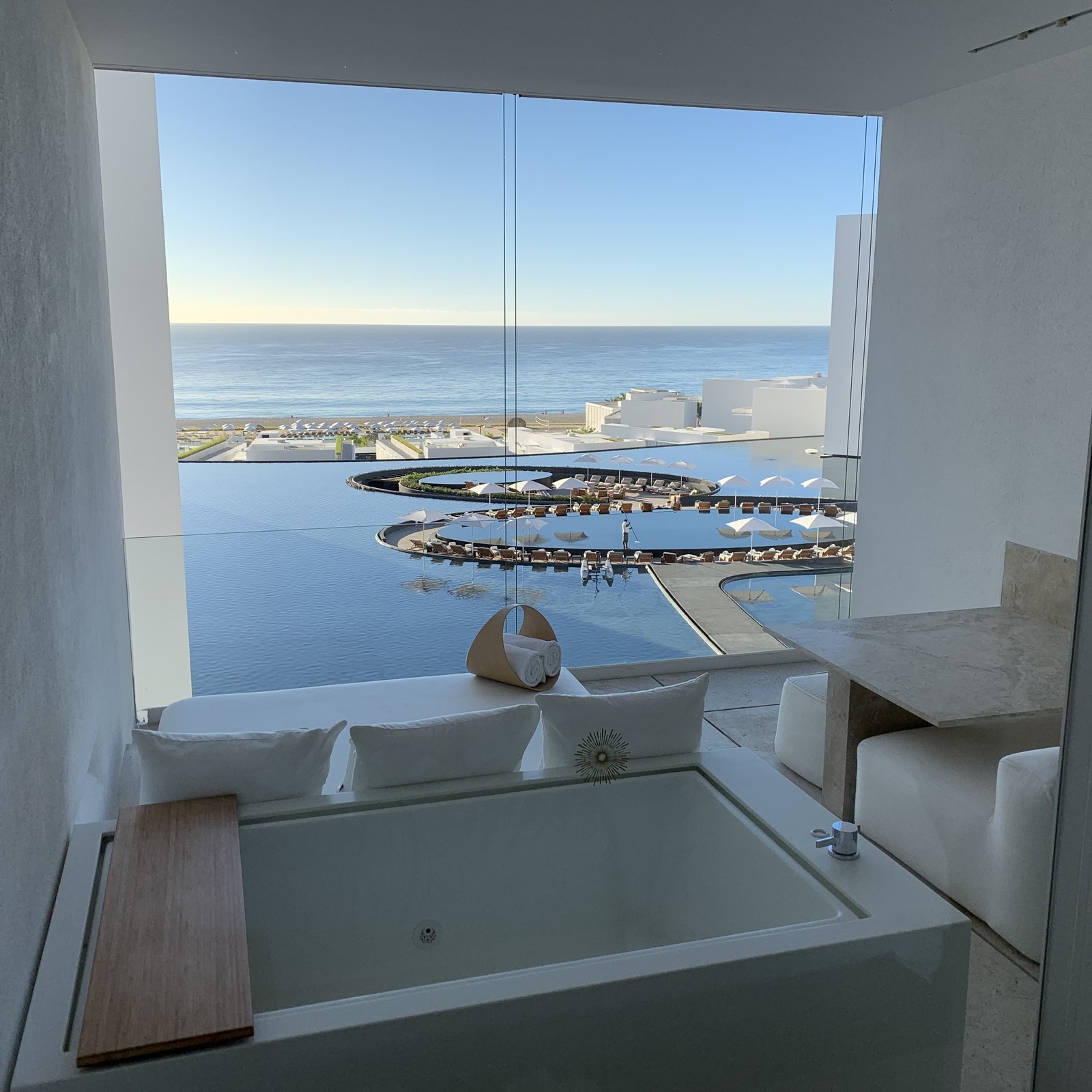 A white tub at the window of a room at Viceroy Los Cabos looking out over the oval pool and the sea