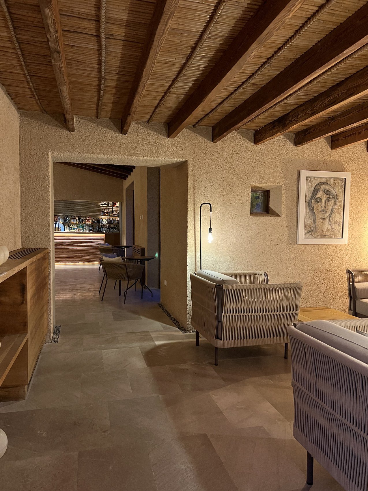 A passage under heavy timber beams opening through to further rooms, with a drawing on the wall