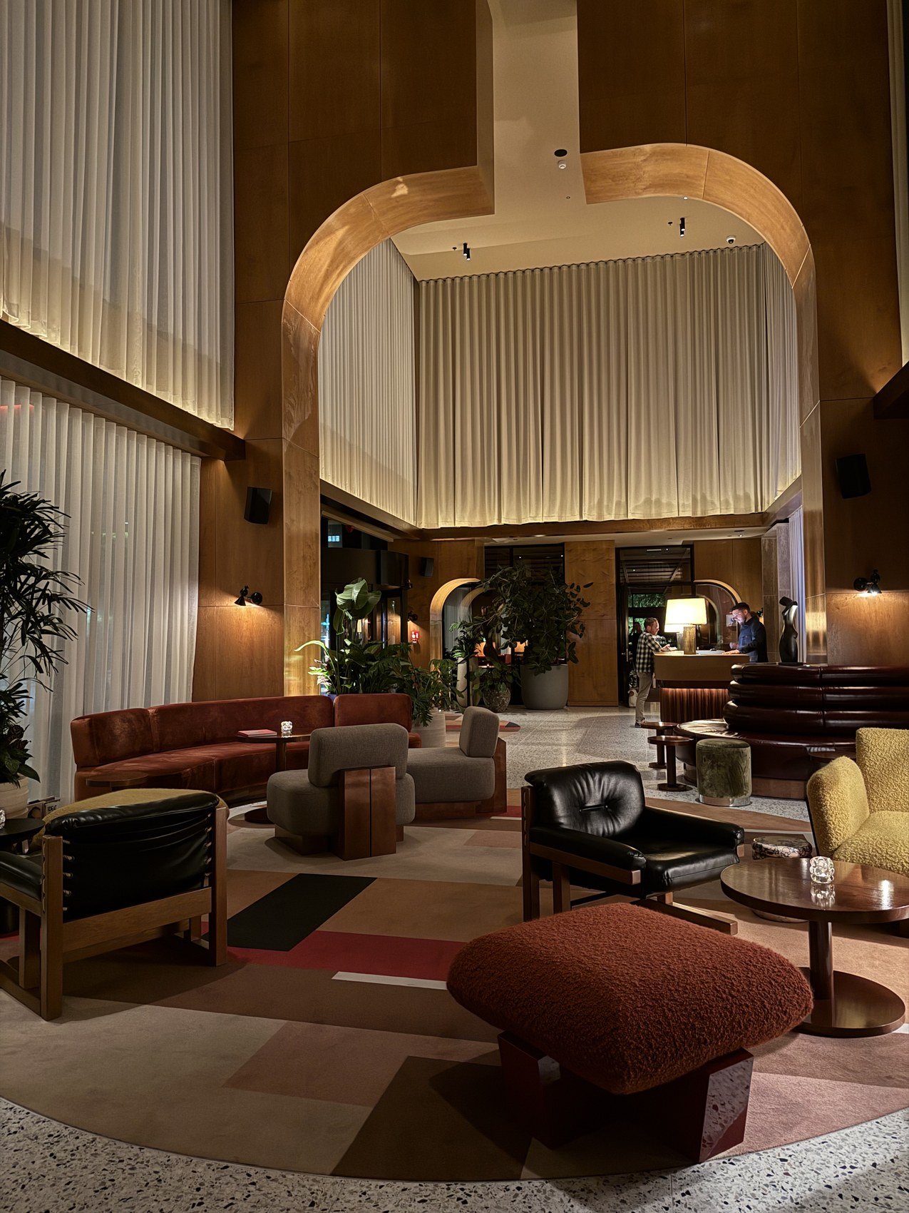A tall lobby under a fluted arch, low sofas on a patterned rug