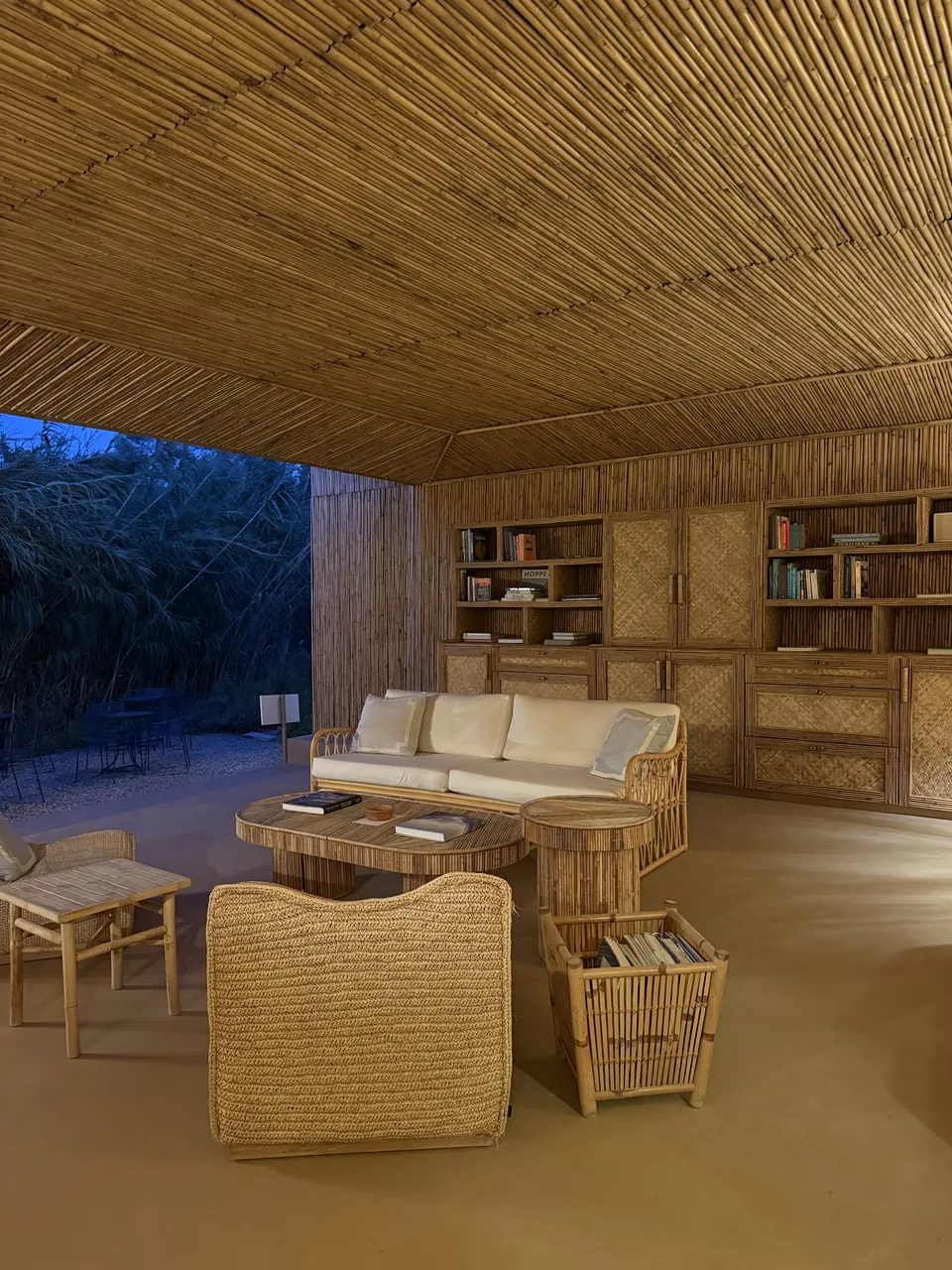 A lounge walled and ceilinged in cane, lit at dusk on Antiparos