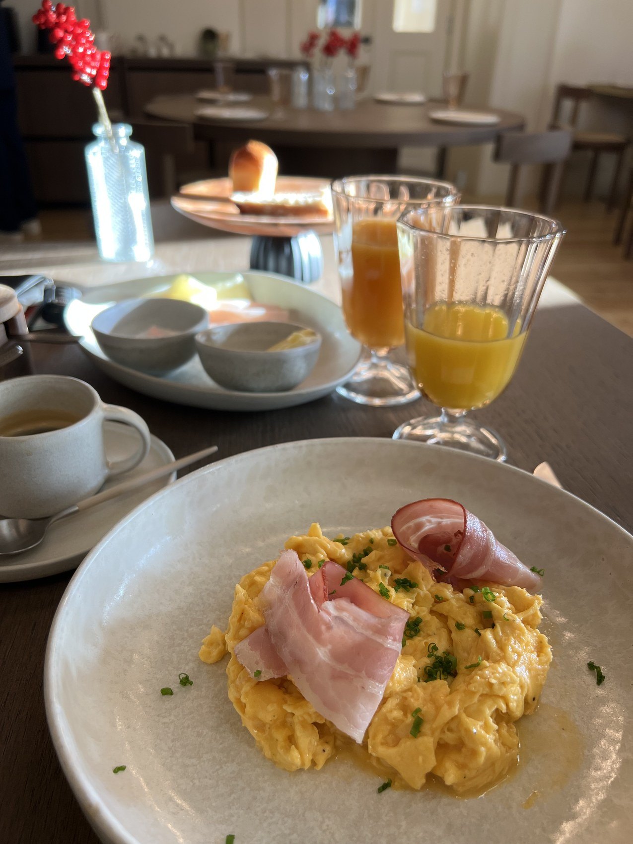 Scrambled eggs with ham, pastries and orange juice laid on a breakfast table
