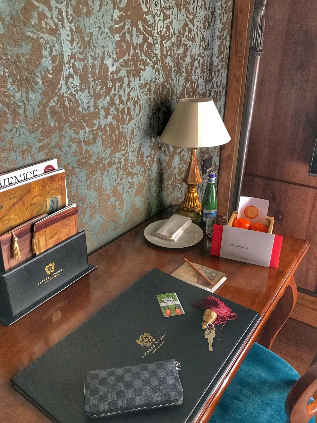 A writing desk with a lamp, a letter rack and room keys on a green blotter