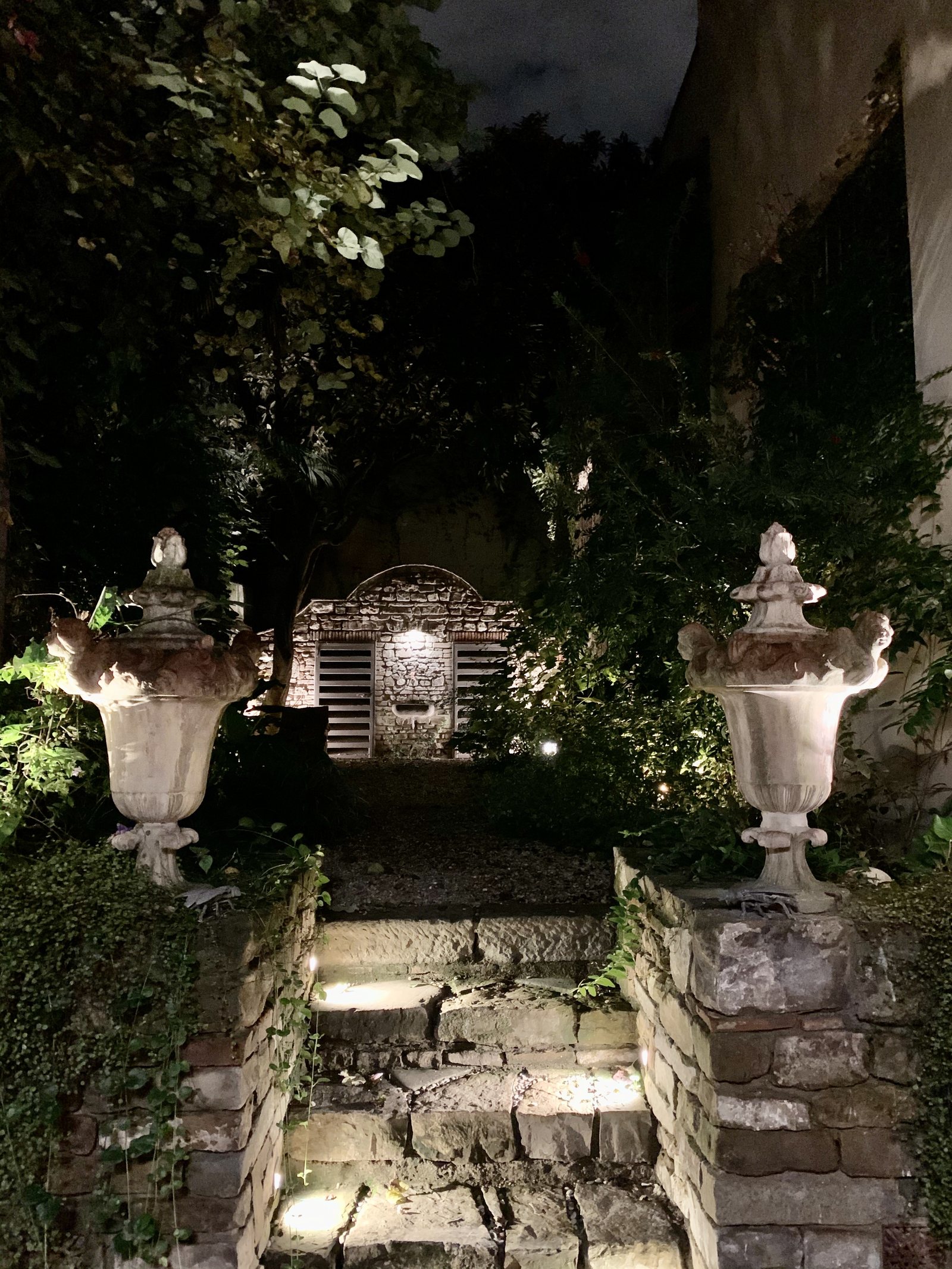 Garden stairs lit at night between two stone urns