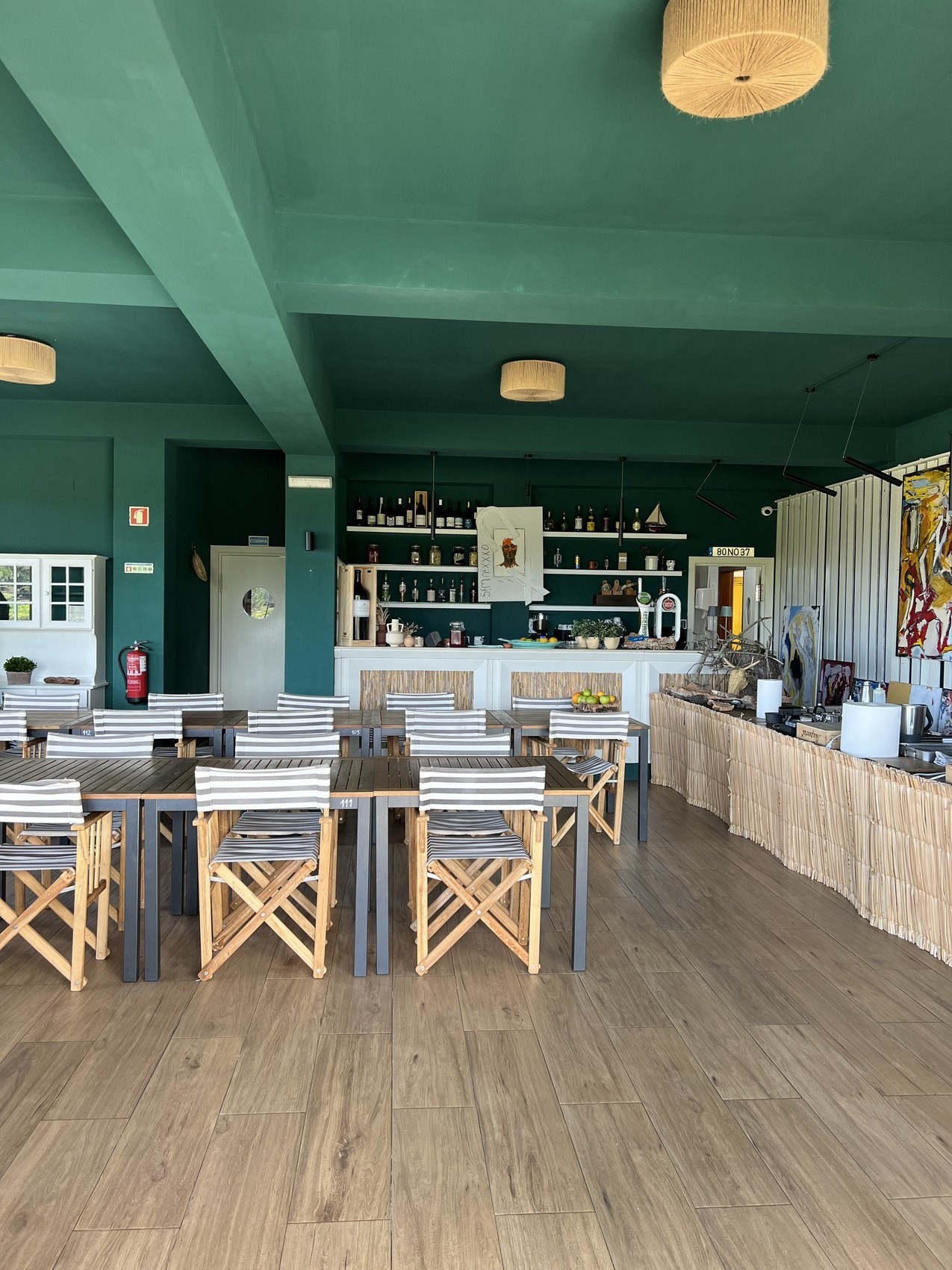 A bar and dining room under a deep green painted ceiling, with director chairs at timber tables