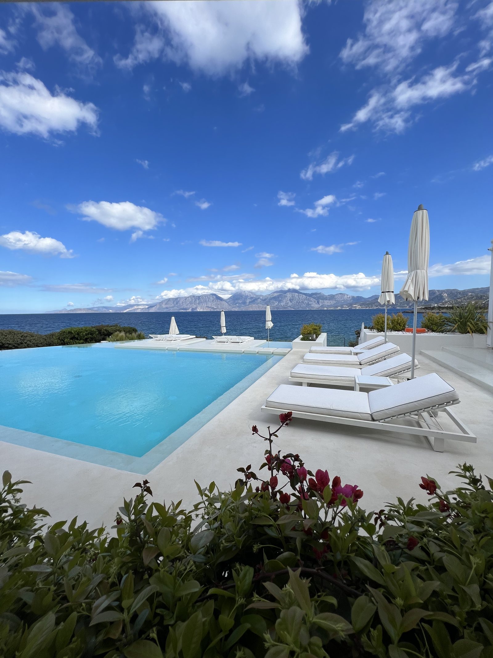 An infinity pool against the sea, with mountains behind it
