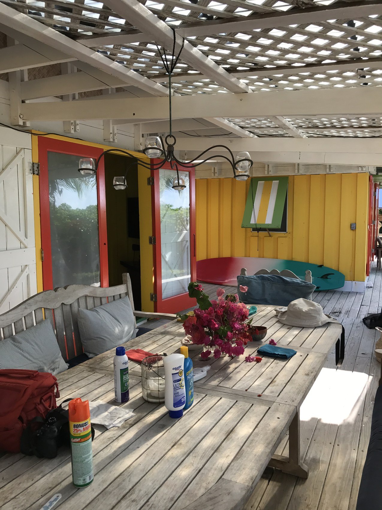 A long table on a veranda under a lattice ceiling, the day's things left on it