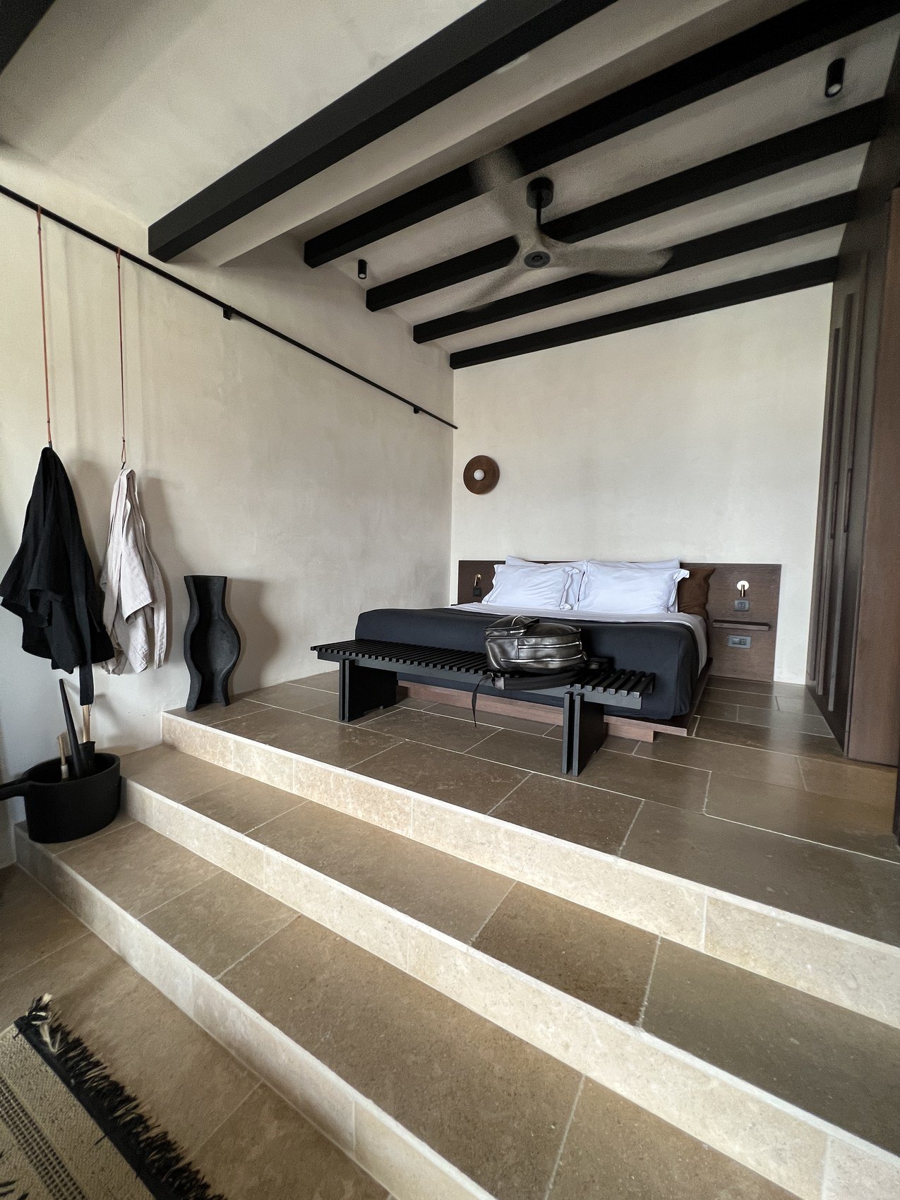 A bed under dark beams, reached by three wide stone steps