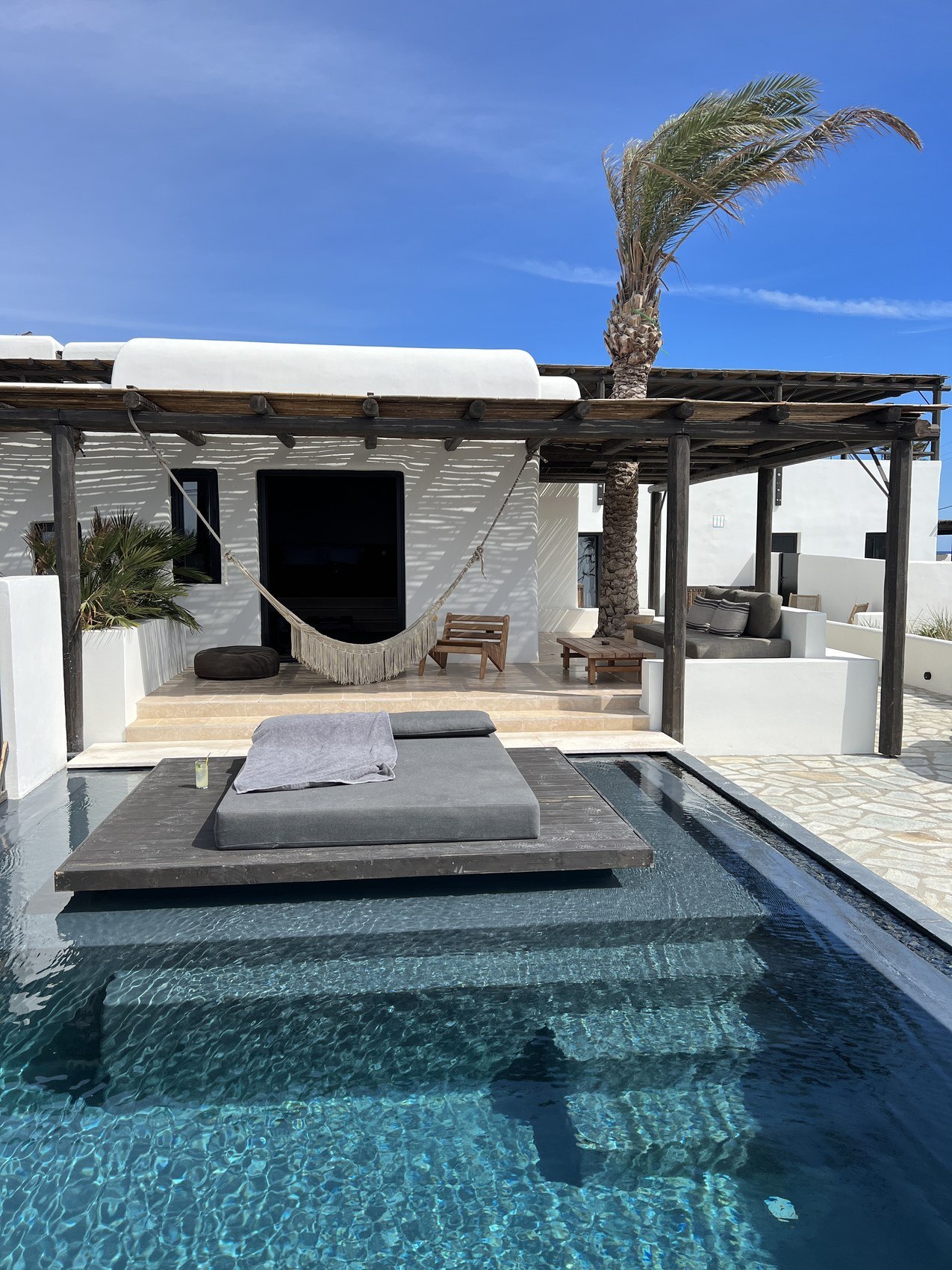 A sunbed standing in a private pool under a timber pergola