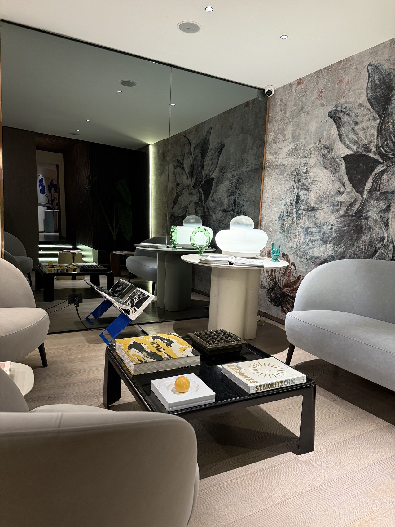 A sitting room in pale greys with a botanical mural along one wall and a low black table