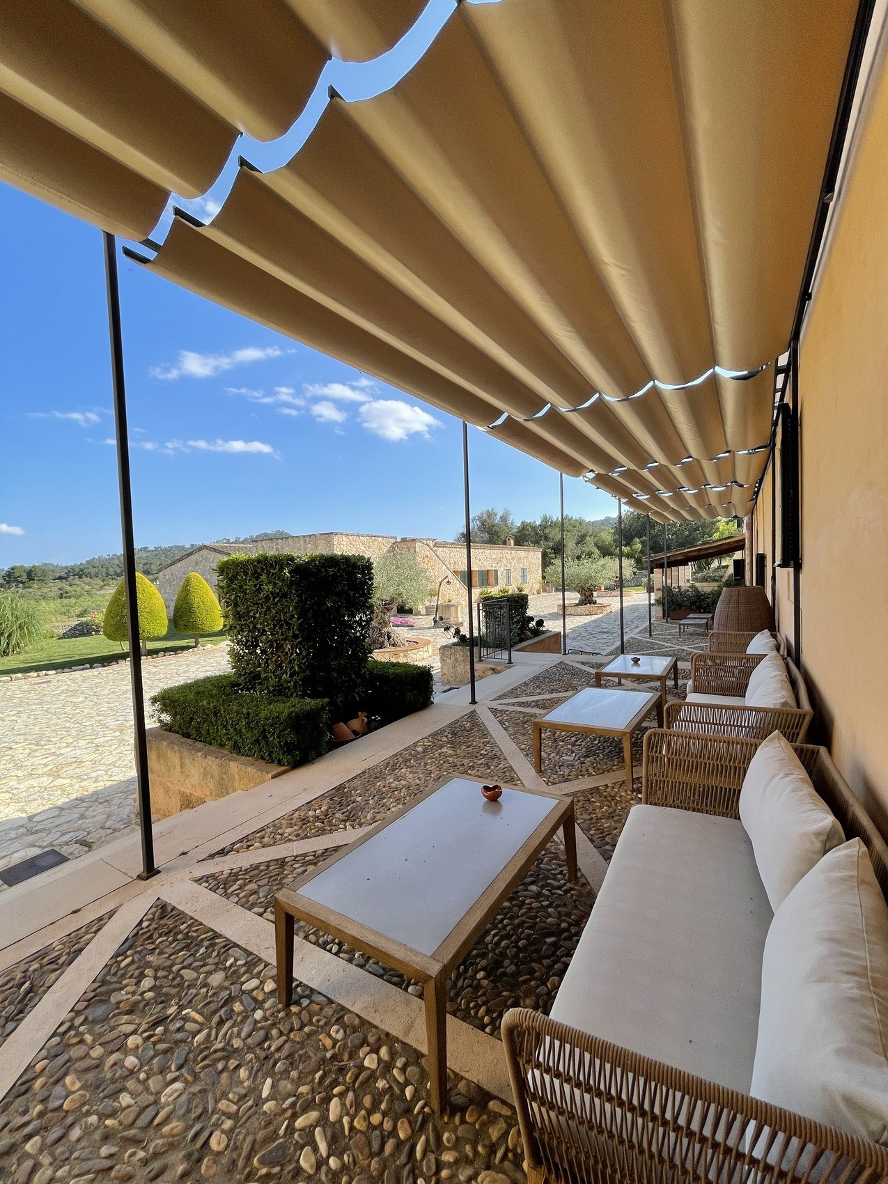 A fluted awning over a terrace of pale sofas looking across open countryside
