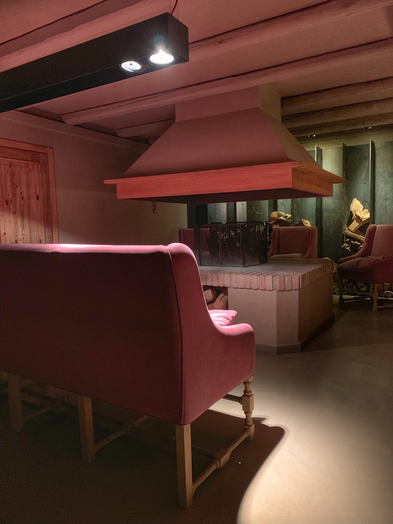 A pink velvet sofa under a pink fireplace hood