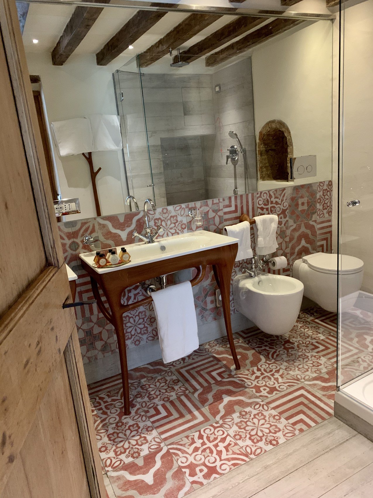 A bathroom with a timber console basin on a red and white patterned tiled floor