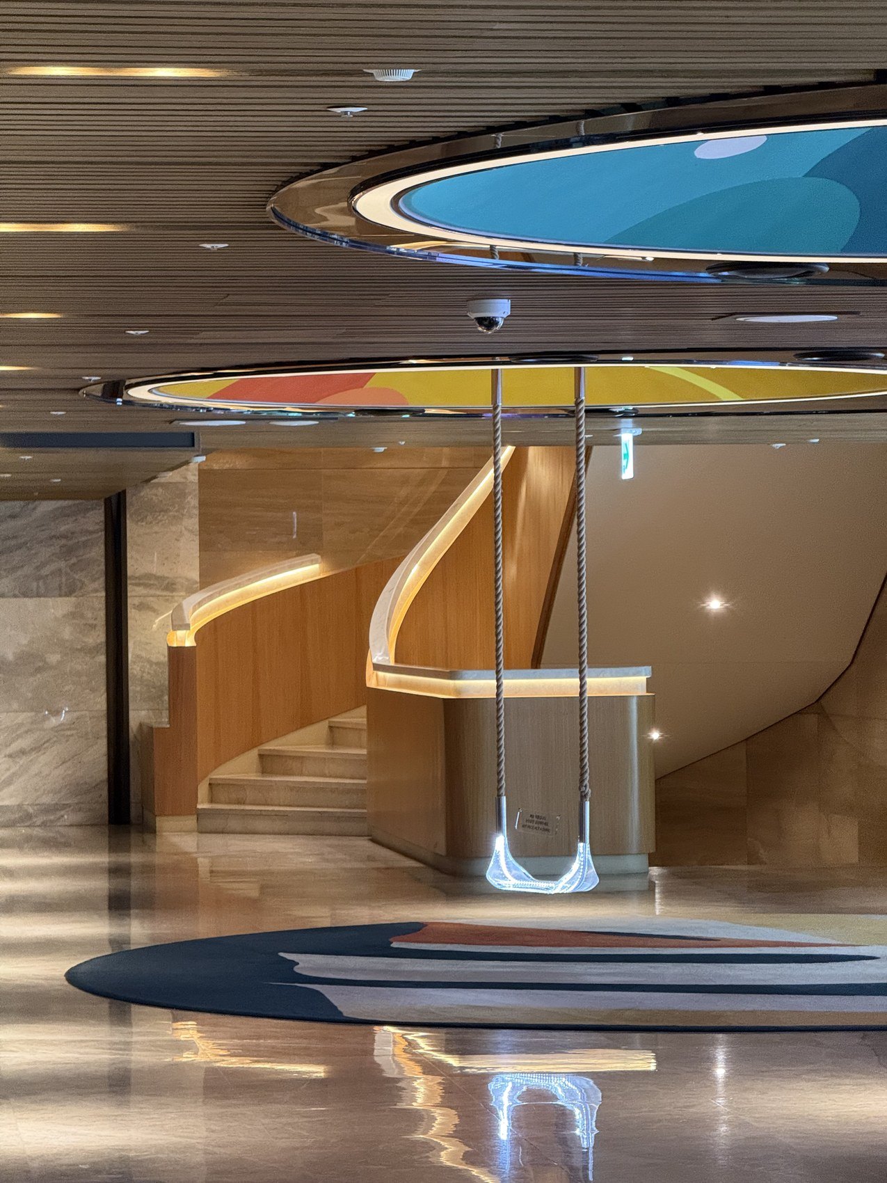 A curved timber staircase under coloured ovals set into the ceiling