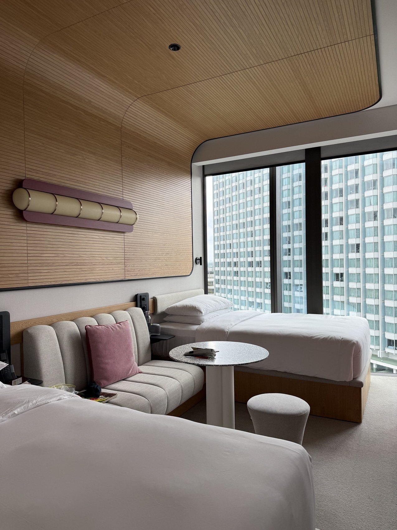 Twin beds and a sofa in a panelled room, towers filling the window