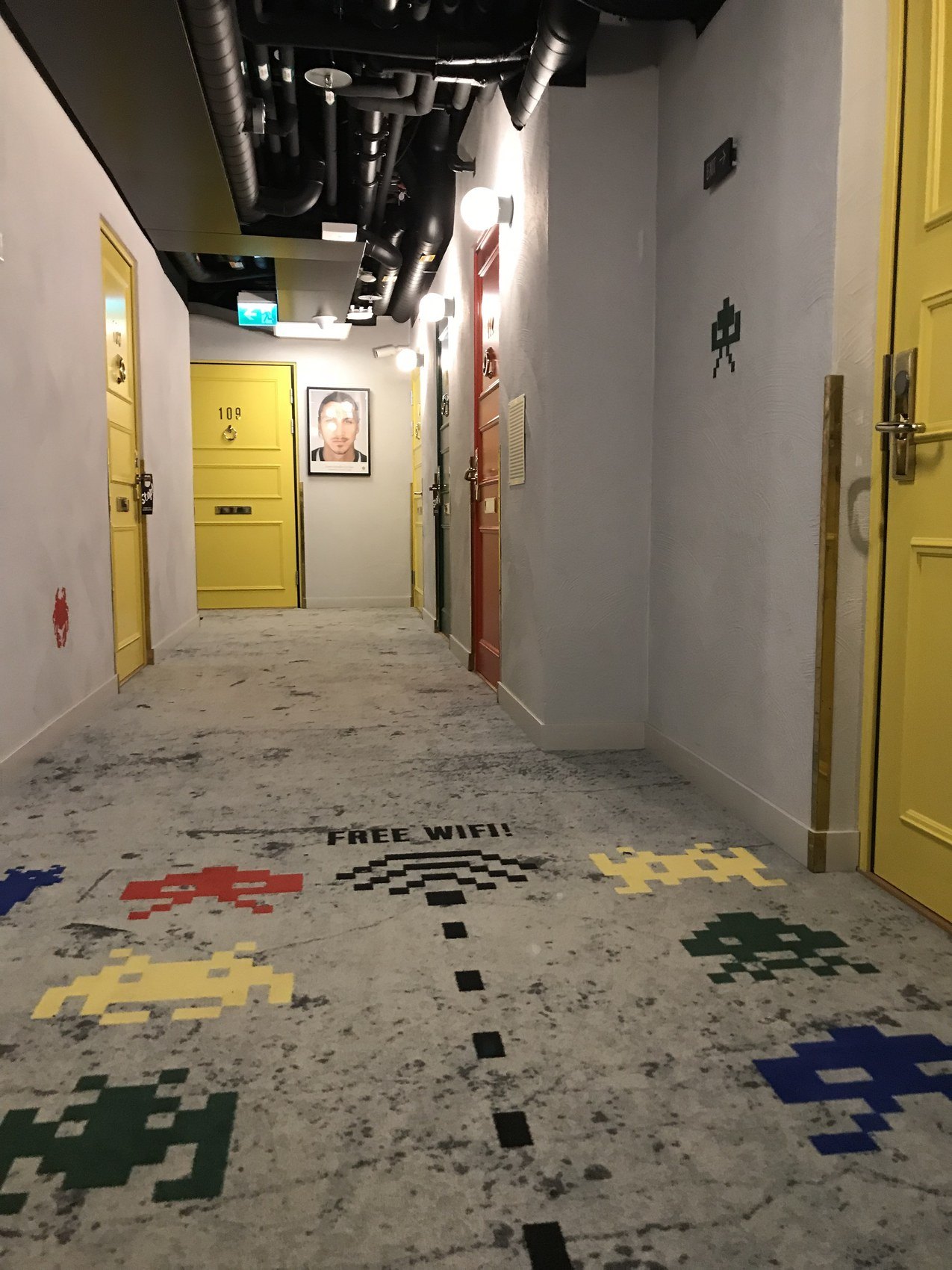 A corridor of yellow doors with pixelated figures laid into the terrazzo floor