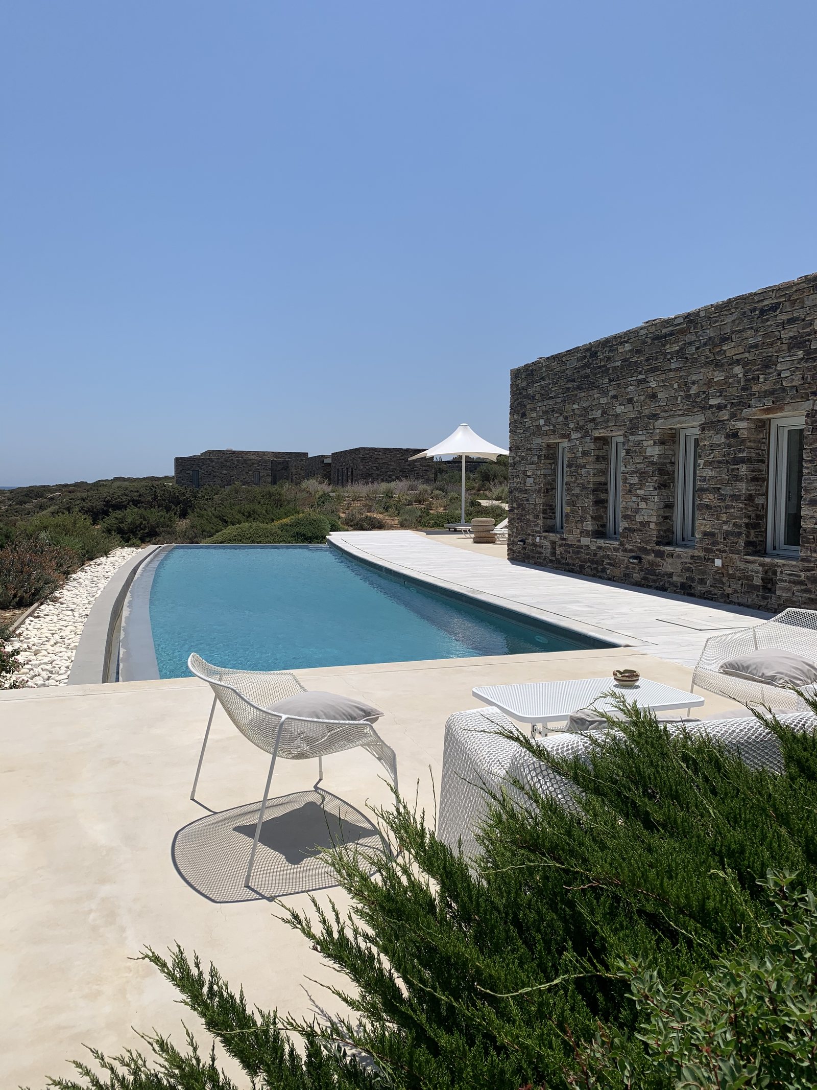 A long pool beside a house of dry stone, a white parasol at the far end
