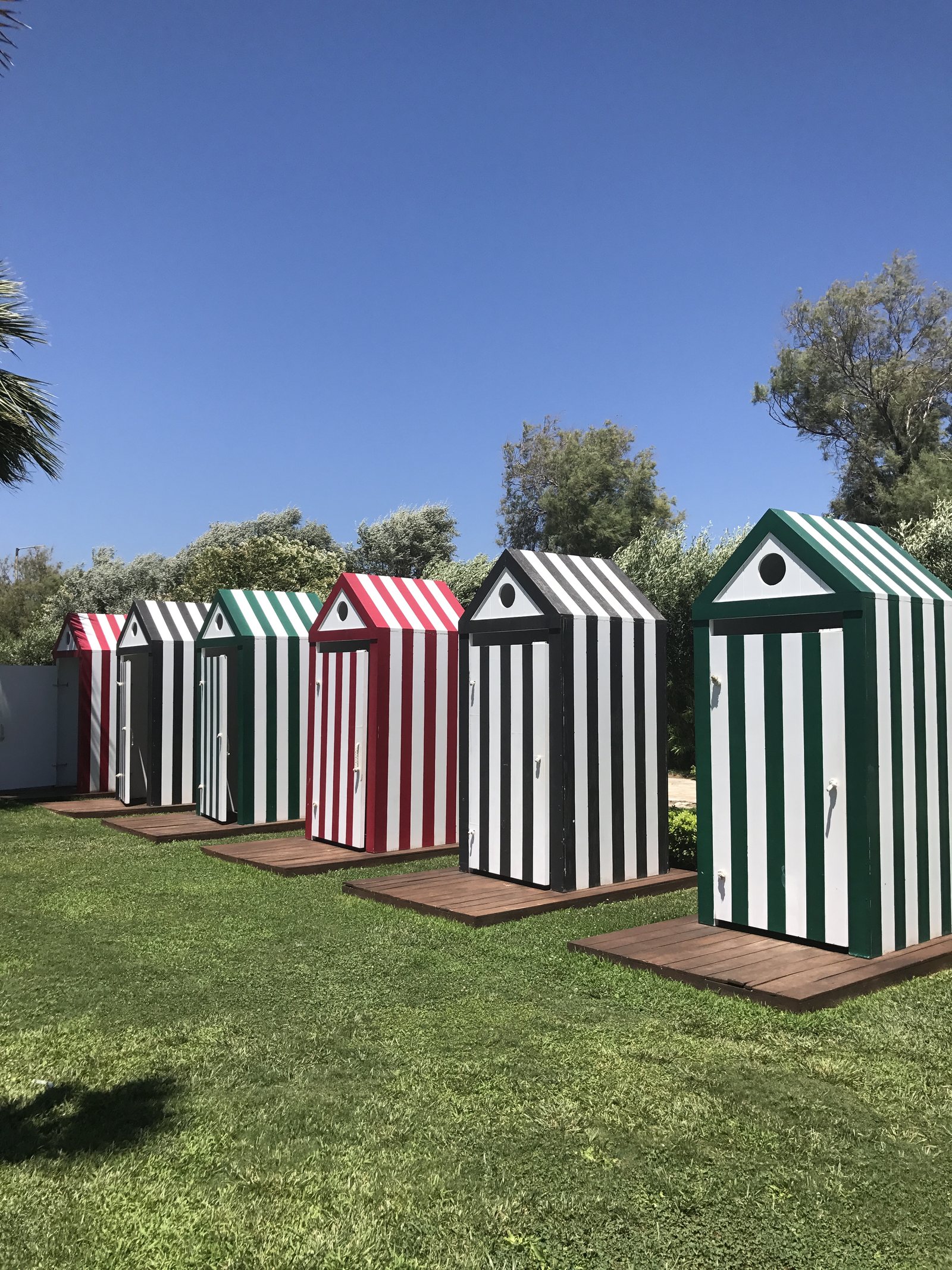 A row of striped beach cabins standing on grass